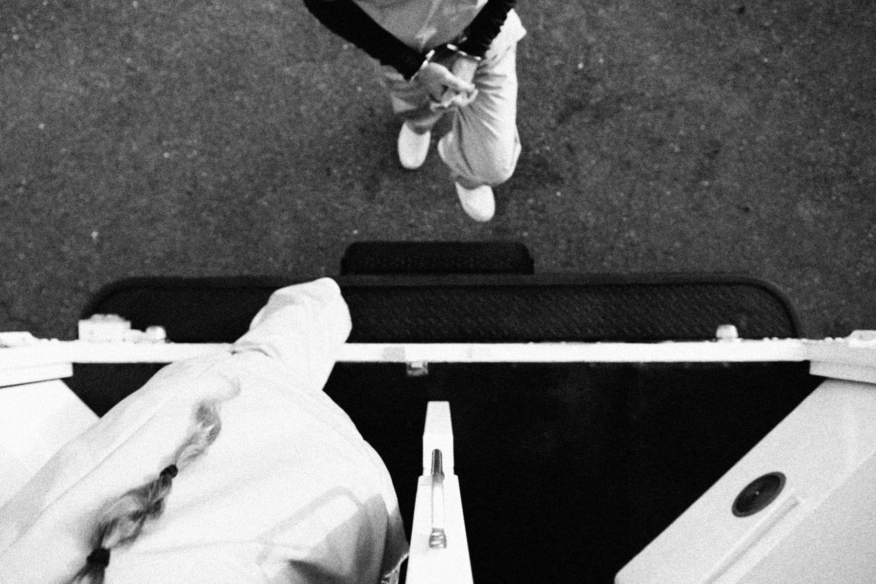 An overhead view of shackled inmates being loaded into the read of the prison transport vehicle