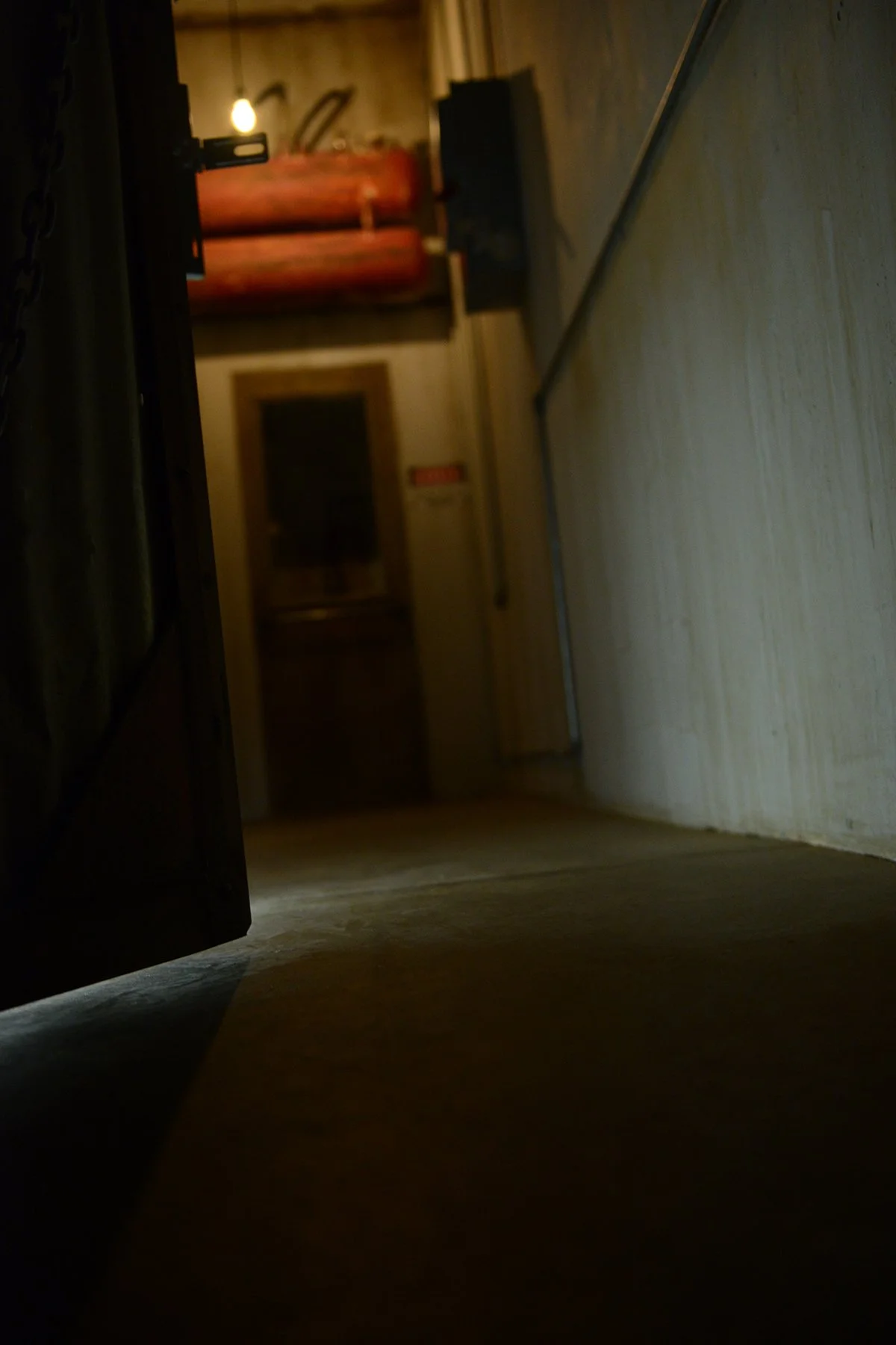 In the distance a closed gas chamber door with large red tanks hanging above