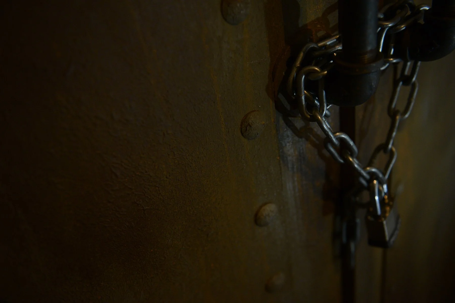 A rusted iron door is chained and padlocked shut