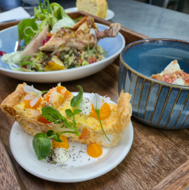 Plated boardroom bento box, plated with butternut squash and goats cheese tart in the foreground