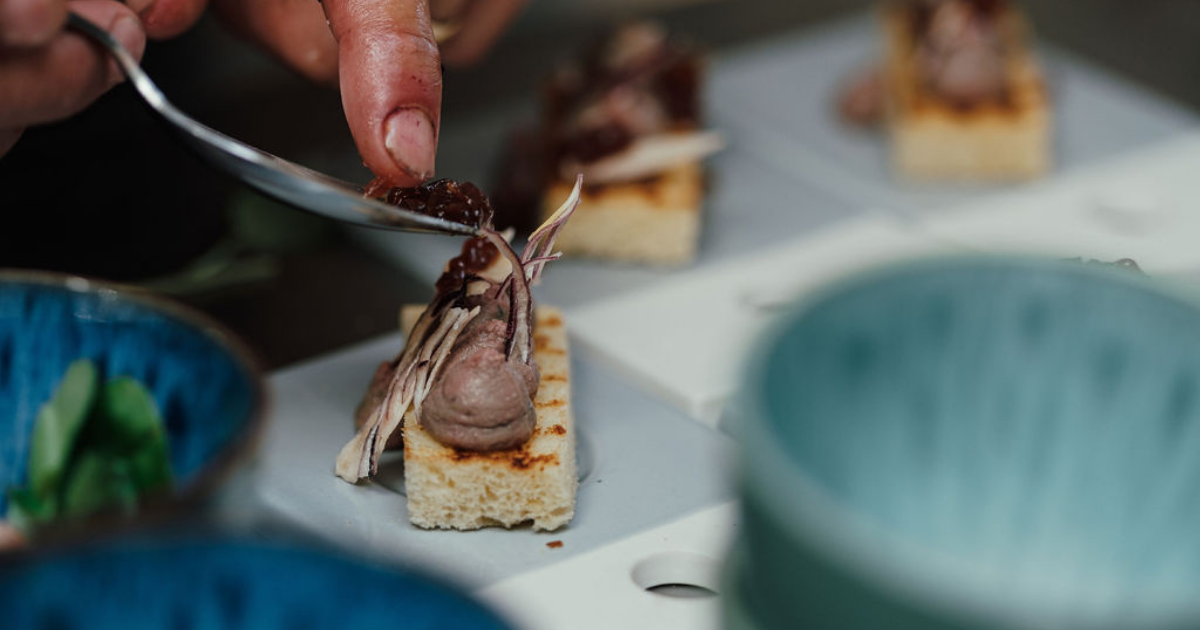 Close up of a Salters Events chef garnishing a chicken parfait dish
