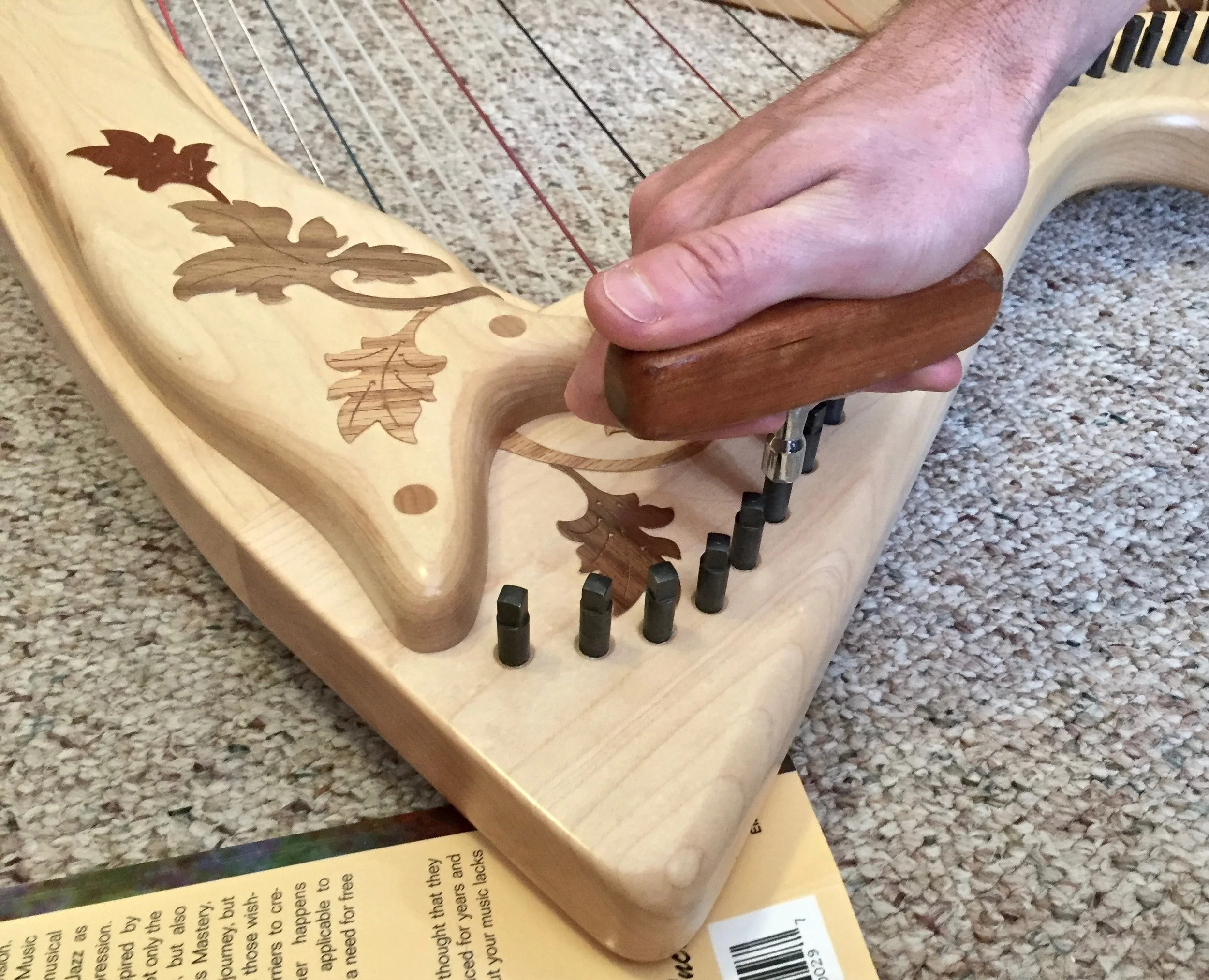 Lay your harp, string side down, with the point on a book and then firmly press the loose pin back in with your tuning wrench.