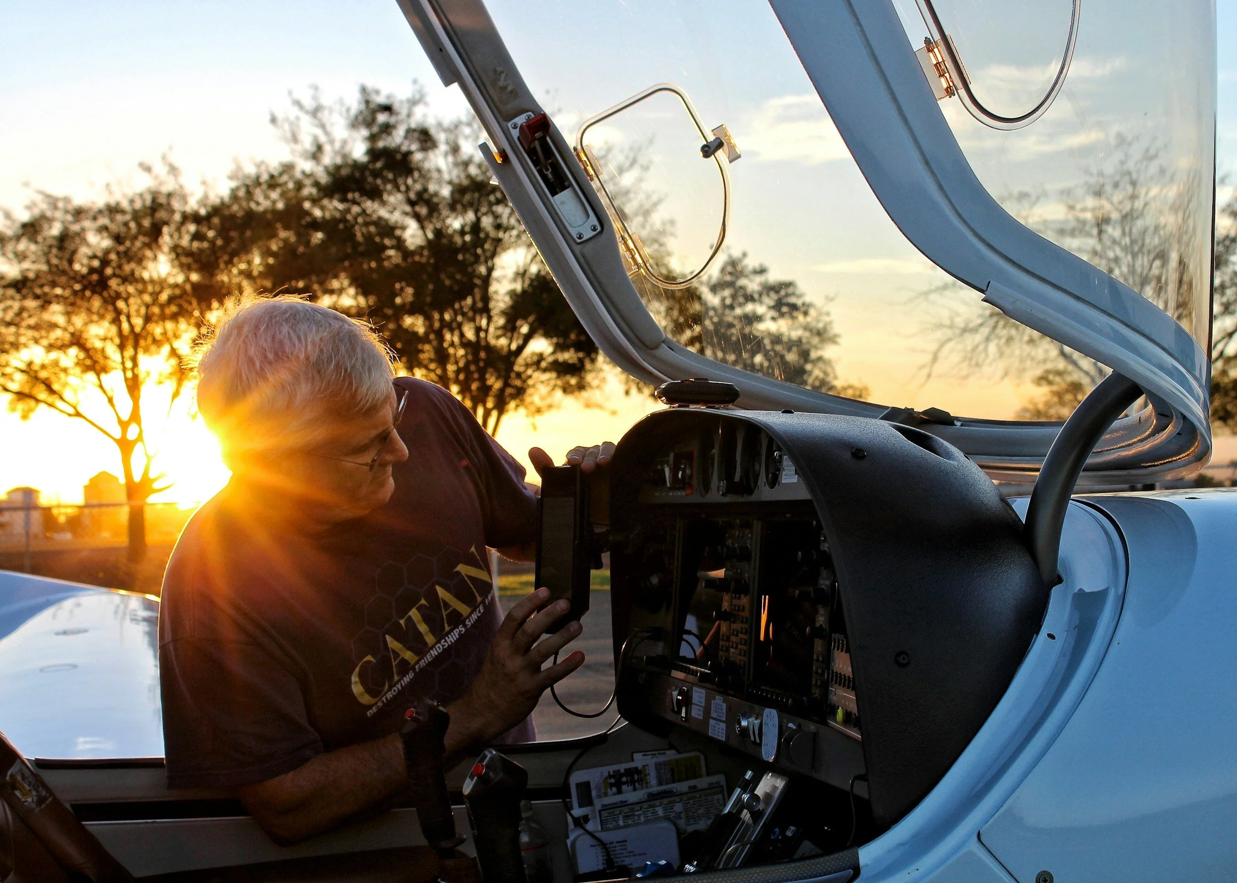 Pilot working in a small aircraft cockpit at sunset