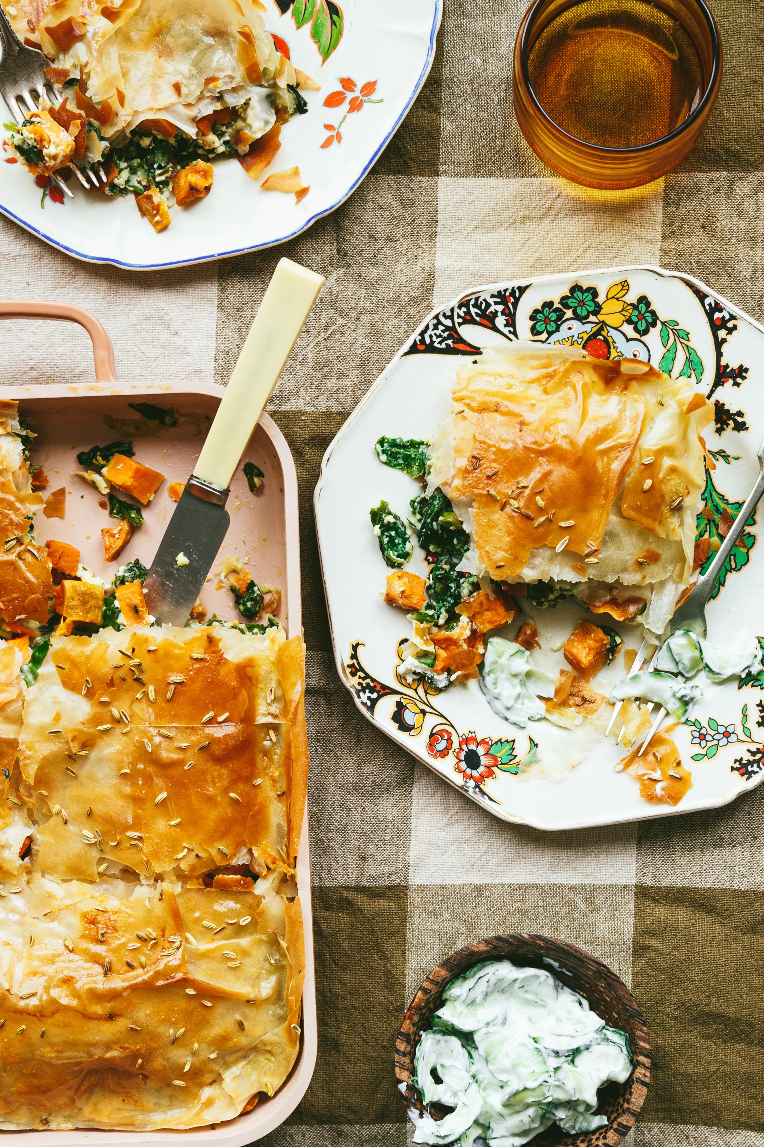 Kimberly Espinel profile image showing a pretty plate and baking dish both containing spinach pie with flaky phyllo pastry