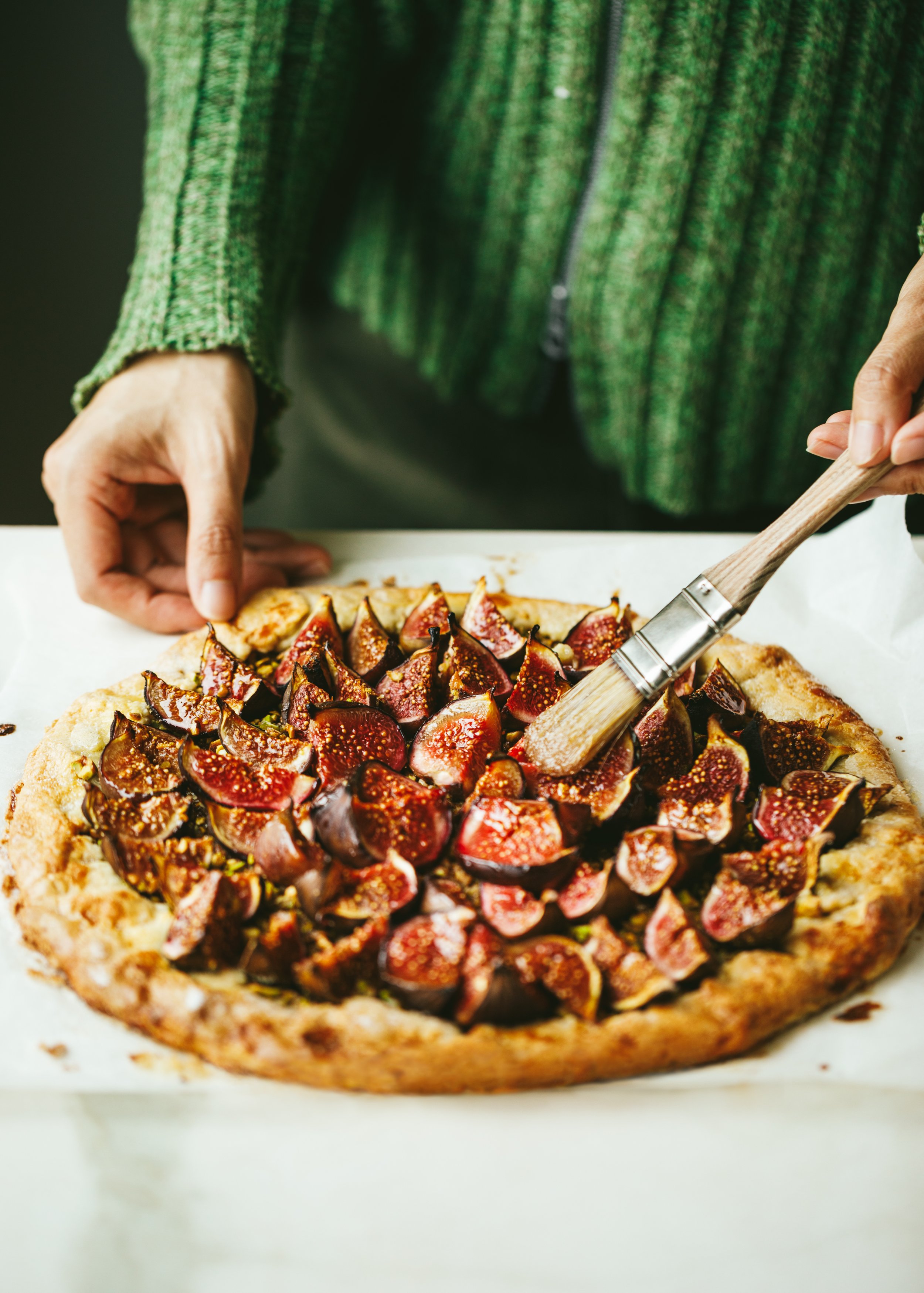 Kimberly Espinel portfolio image showing hands brushing egg wash over a fruit tart with figs