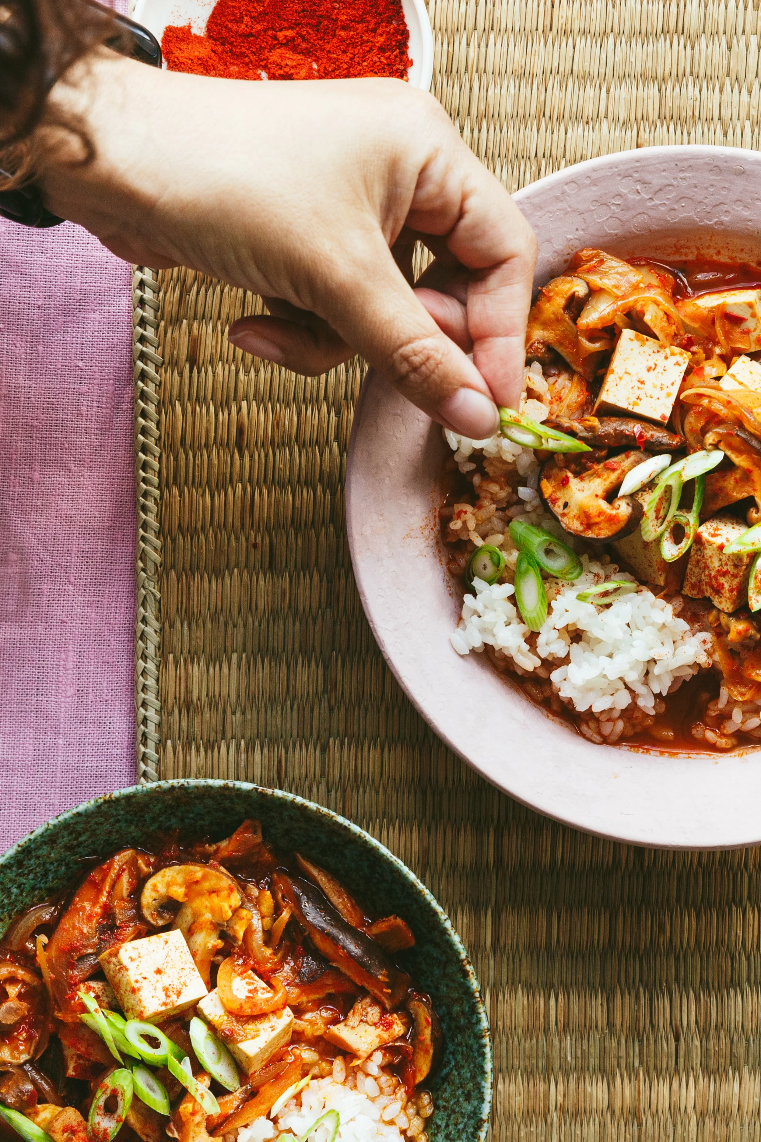 Blog post showing a hand putting the finishing styling touches on a dish with rice, mushrooms and tofu