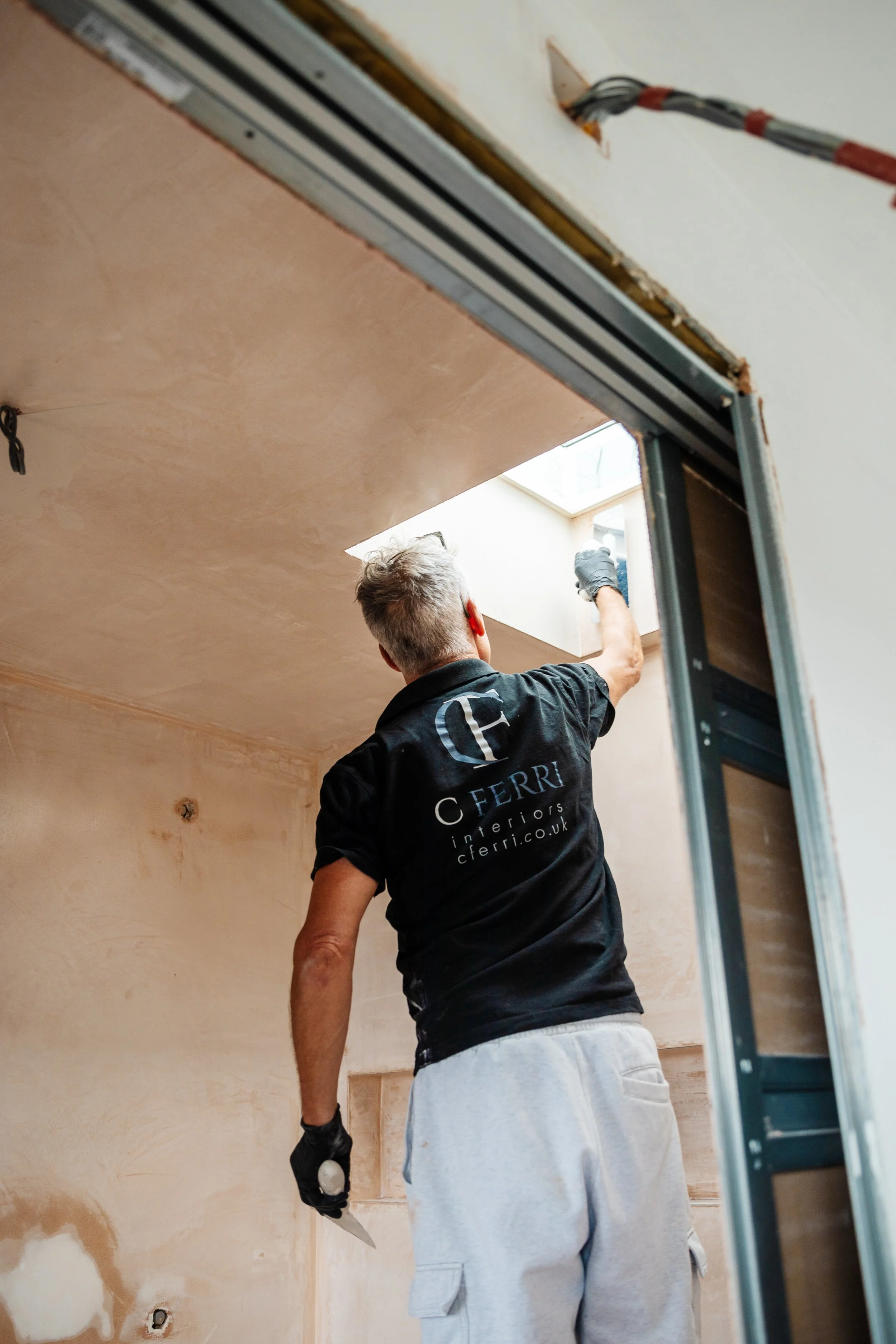 Blog post image showing a workman plastering a wall near a skylight