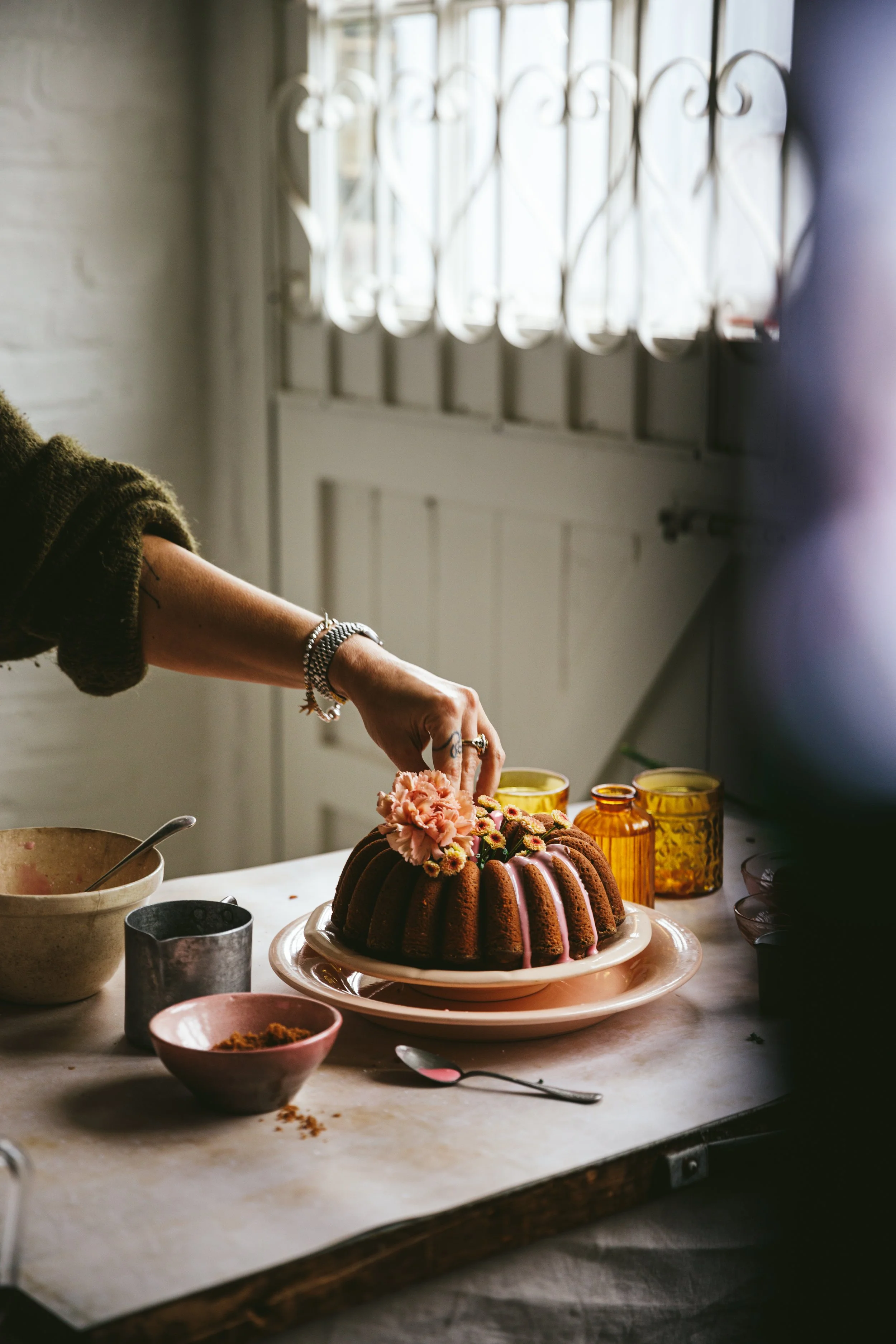 Blog post image showing a hand place a flower on a decorated bundt cake