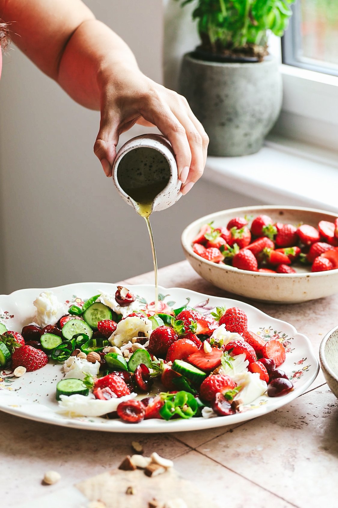 Blog post image showing hands pouring dressing from a small ceramic jug over a salad on a platter