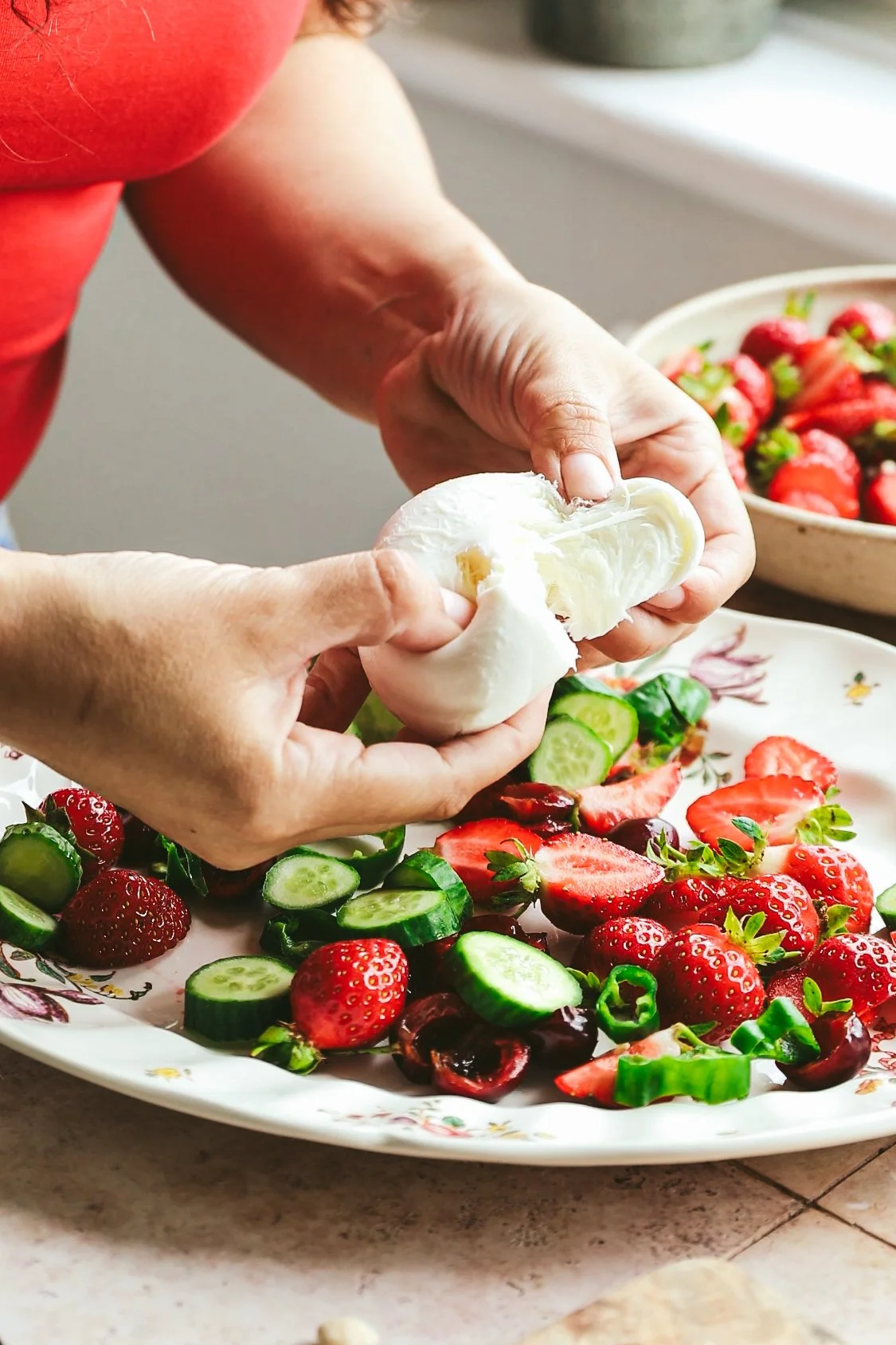 Blog post image showing hands tearing a ball of mozzarella over a platter of salad