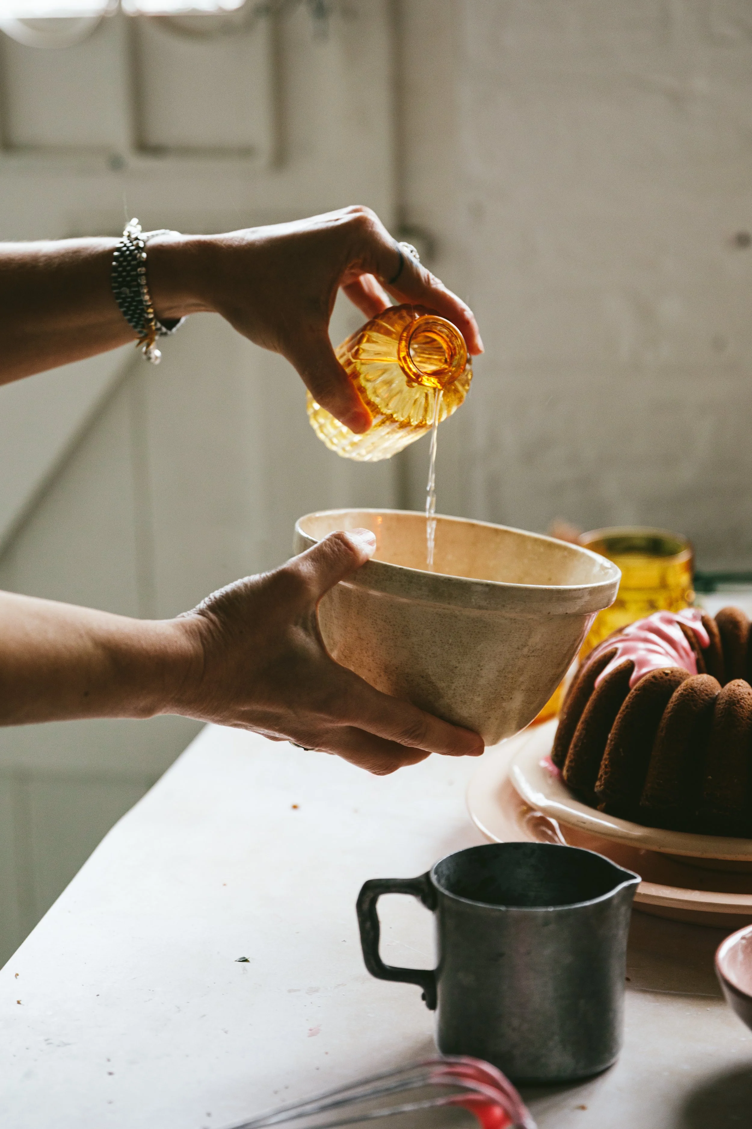 Blog post image showing hands holding a mixing bowl while pouring water in from a pretty amber coloured glass bottle
