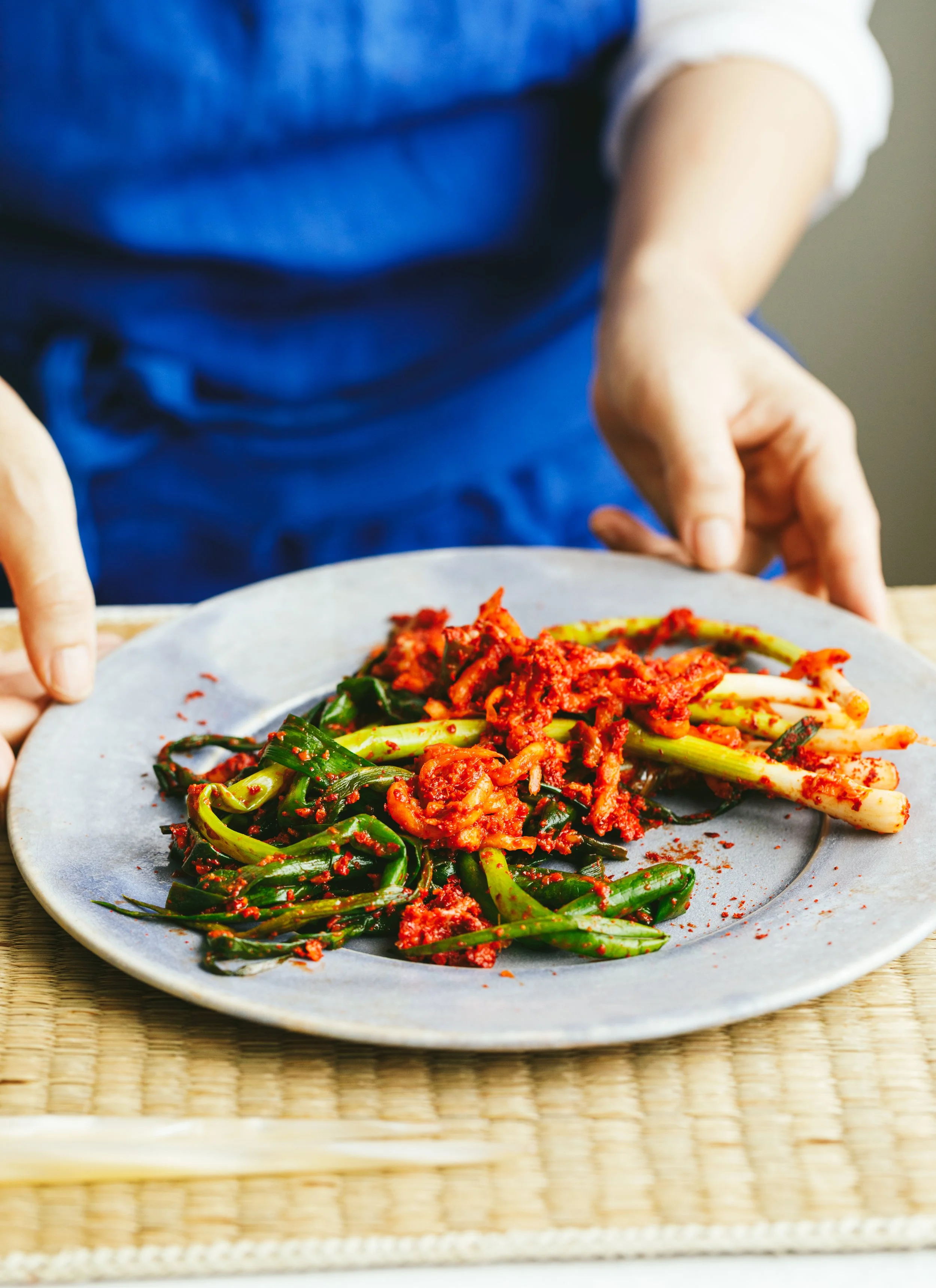 Kimberly Espinel portfolio image showing hands holding a plate of kimchi and greens.