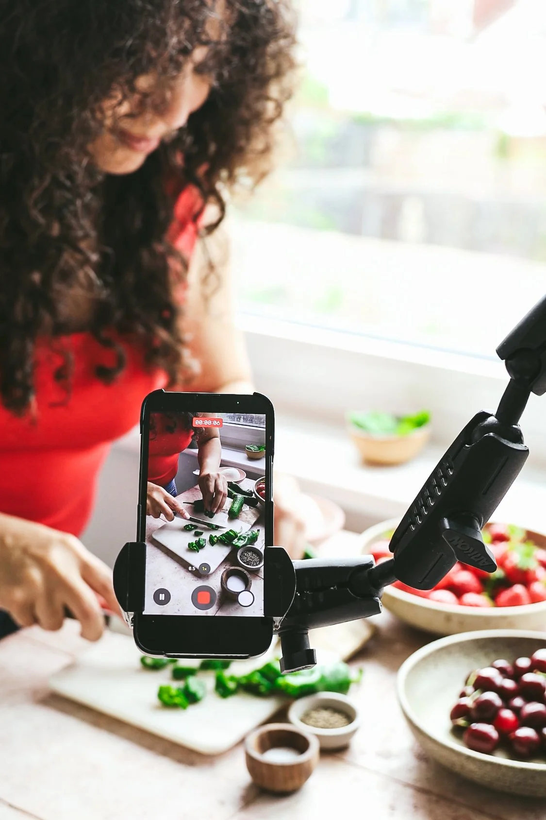 Blog post image showing a phone on a tripod filming a scene in which the author is slicing peppers