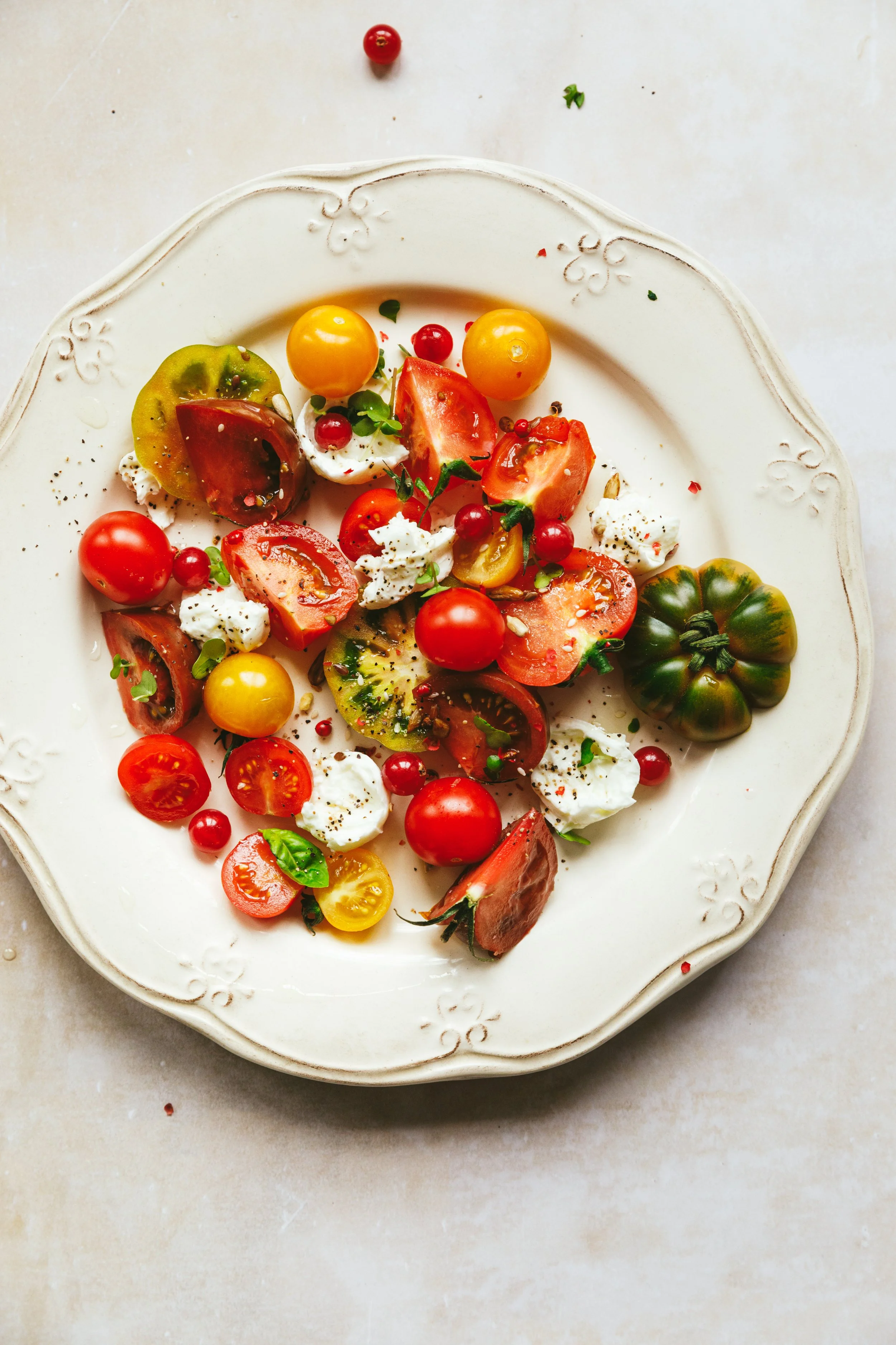 Blog post image showing a colourful tomato salad on a plate with a pretty border