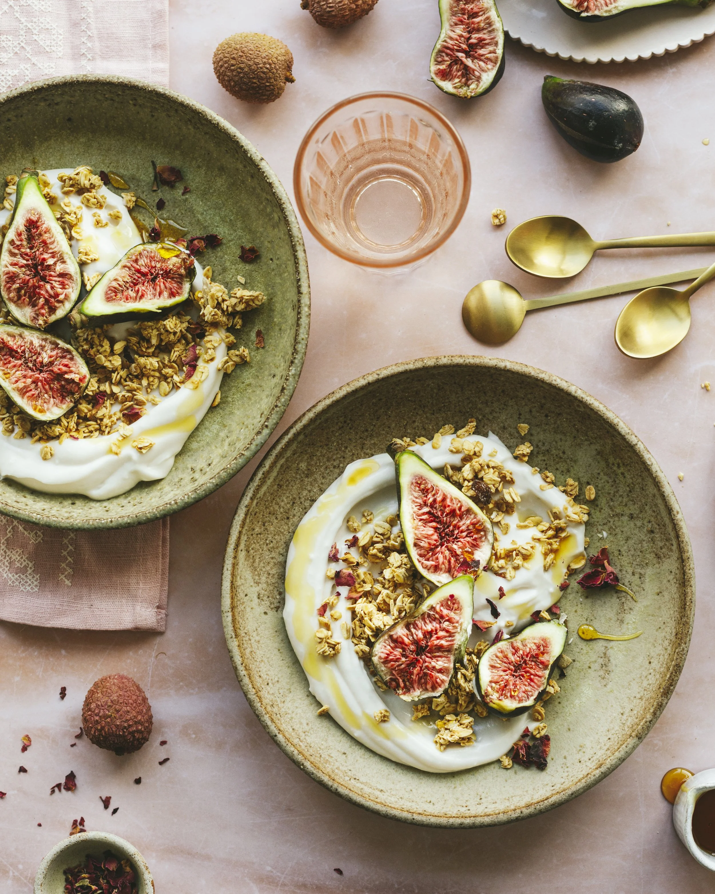 Image shows two breakfast bowls with yoghurt and granola, garnished with halved figs