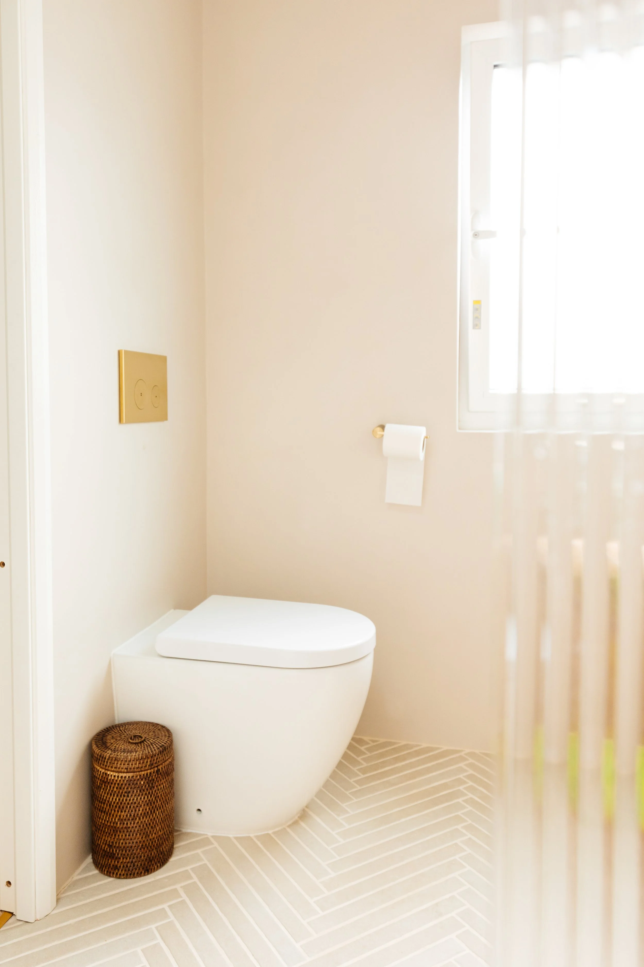 Blog post image showing a bright bathroom corner with a toilet, wicker basket and built in cistern