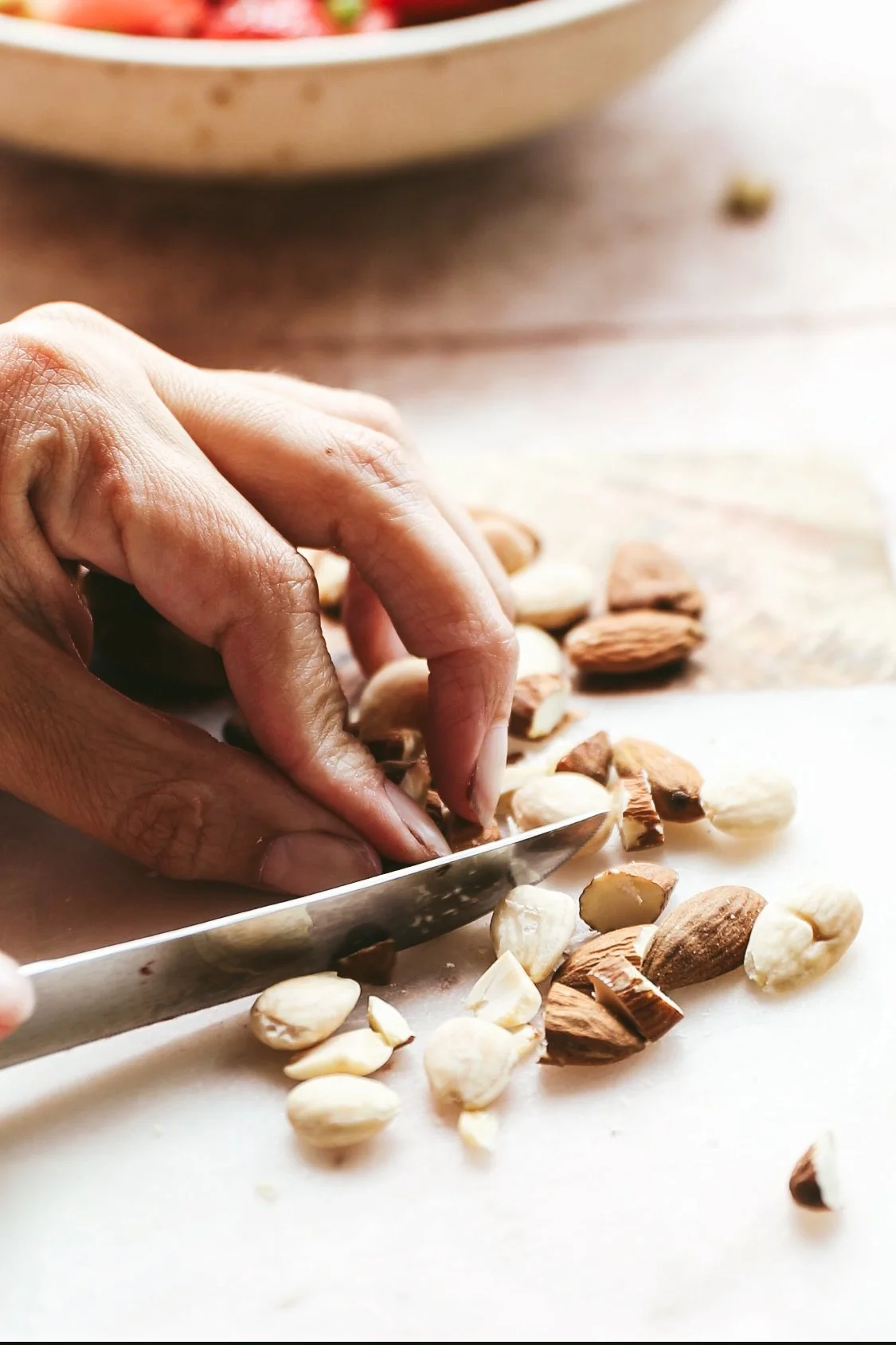 Blog post close up image showing hands chopping almonds
