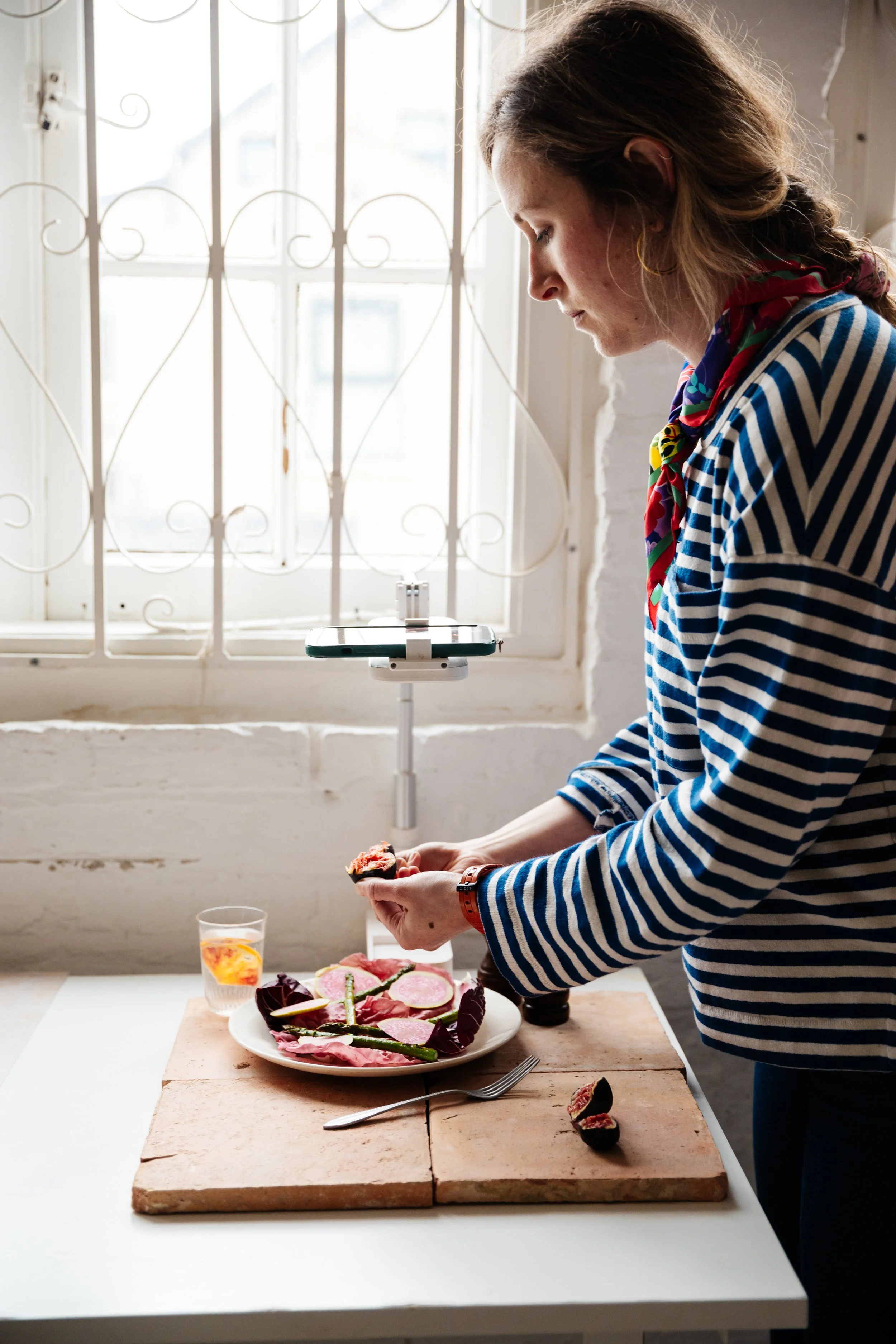 Blog post image showing a person styling a salad, while a smart phone on a stand is filming her actions