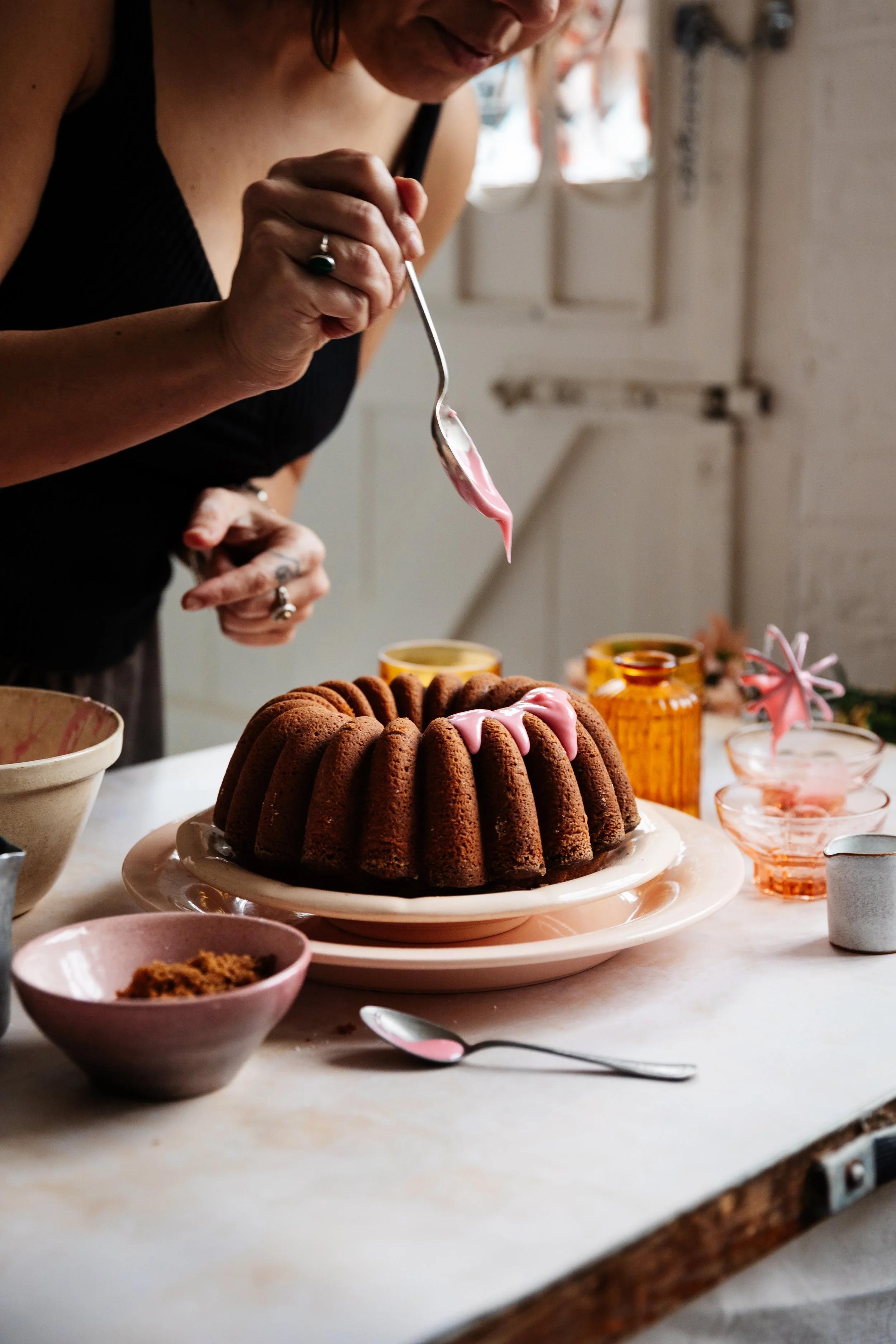 Blog post image showing a person spooning pink icing over a bundt cake