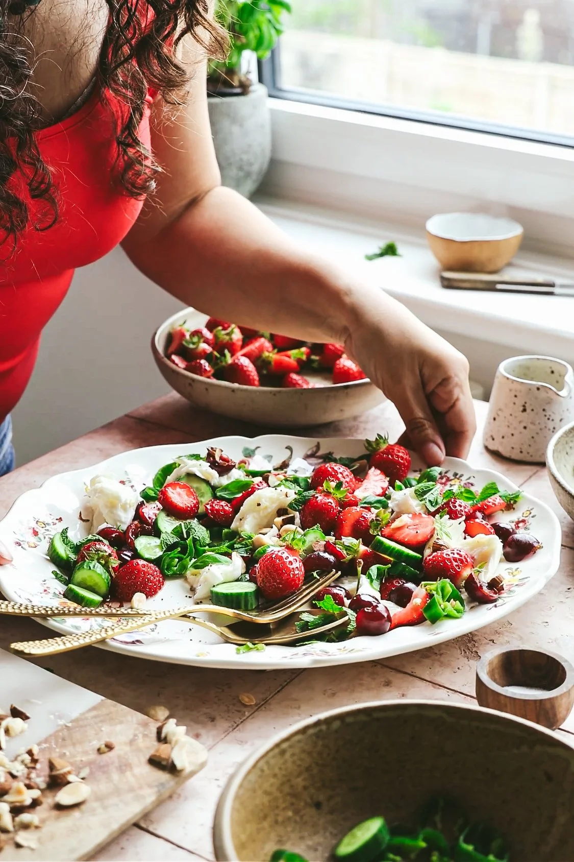Blog post image showing author Kimberly (only arms visible) holding a platter of strawberry and mozzarella summer salad