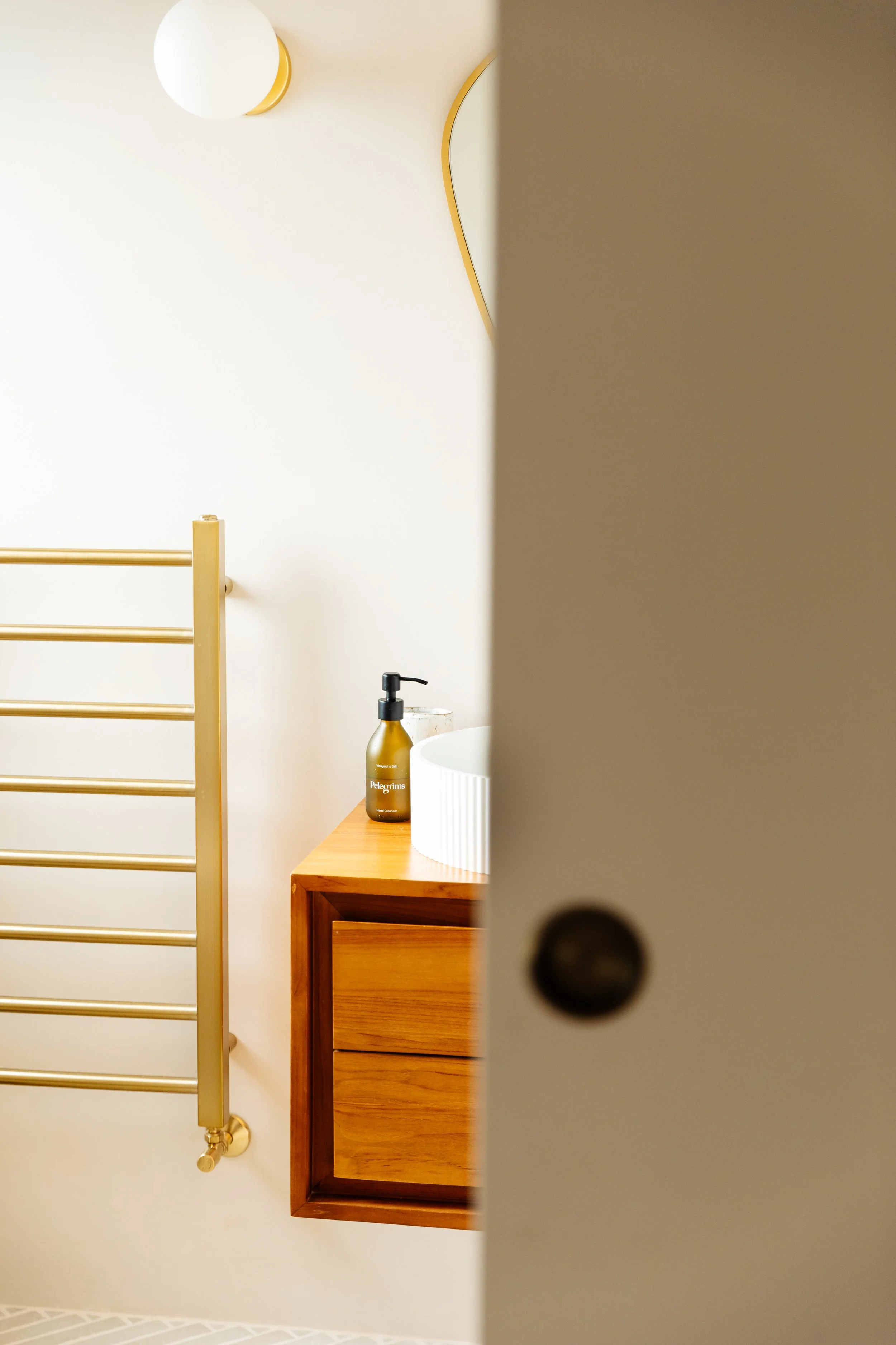 Blog post image showing a peek-in view from the half-open door of the bathroom with the heated towel rack and floating vanity unit