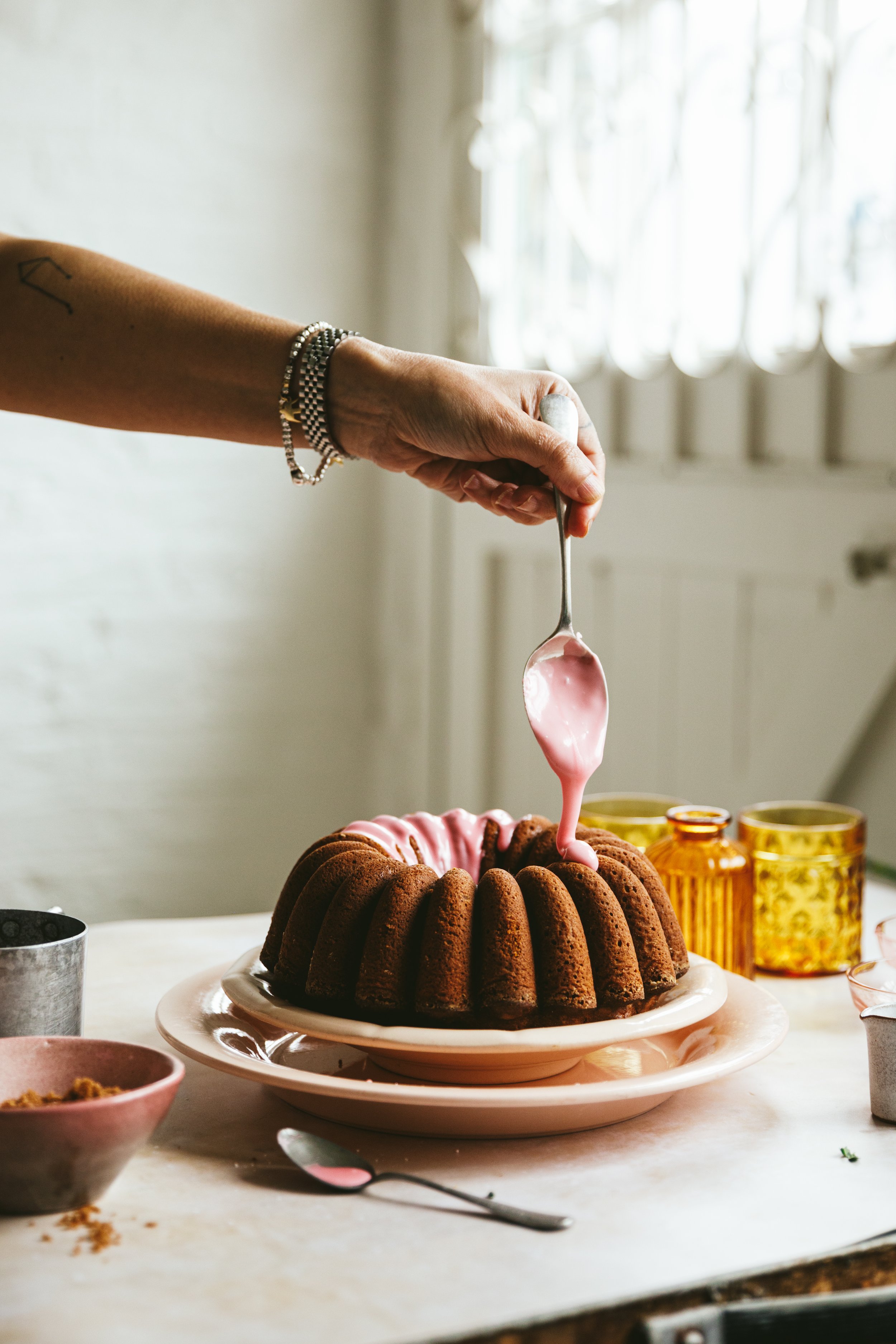 Blog post image showing a hand spoon icing over a bundt cake