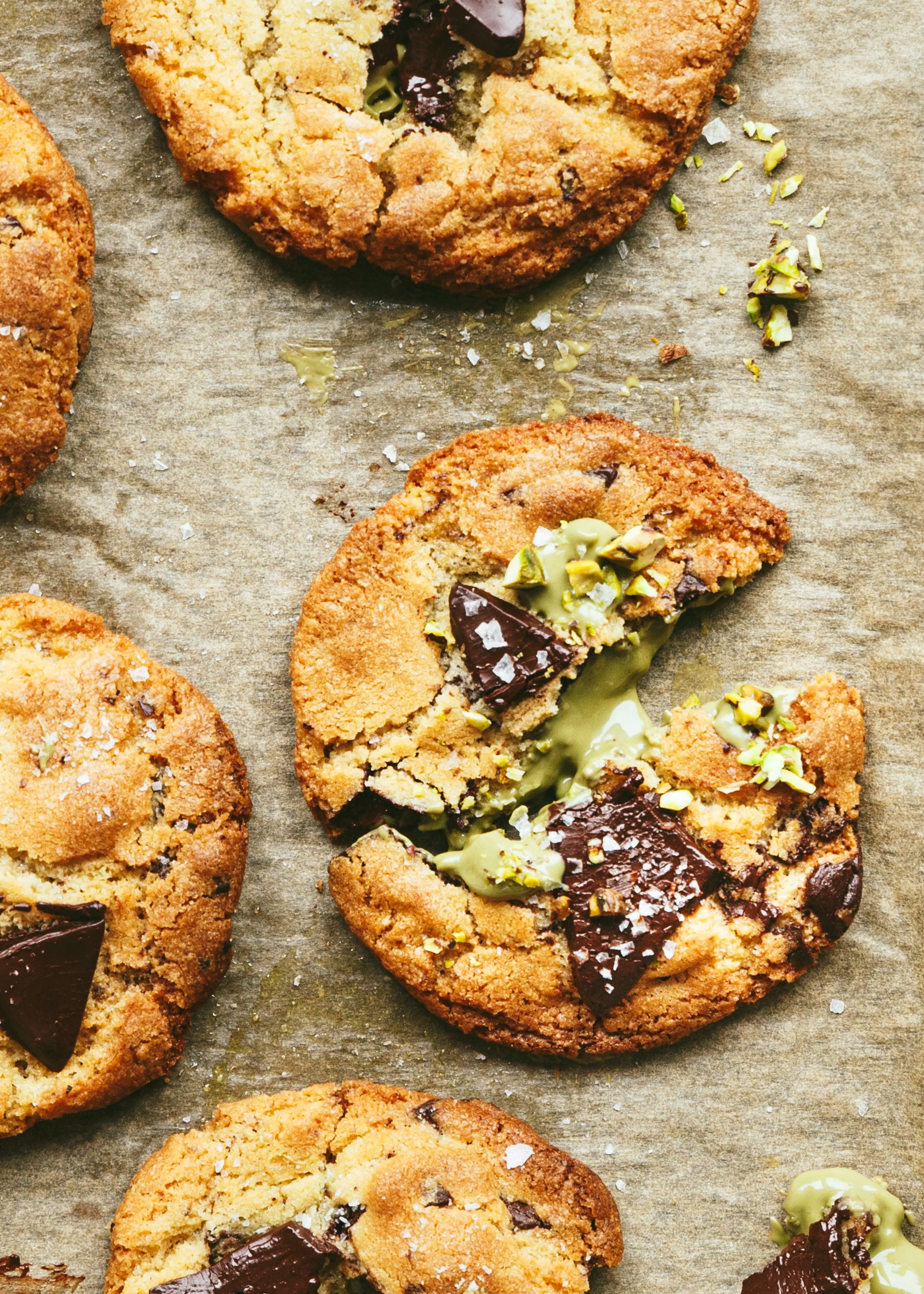 Kimberly Espinel portfolio image showing a close up of cookies on parchment paper with chocolate chunks and pieces of pistachio