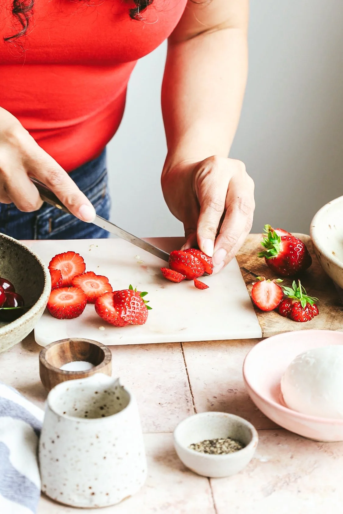 Blog post image showing hands slicing strawberries on a marble chopping board