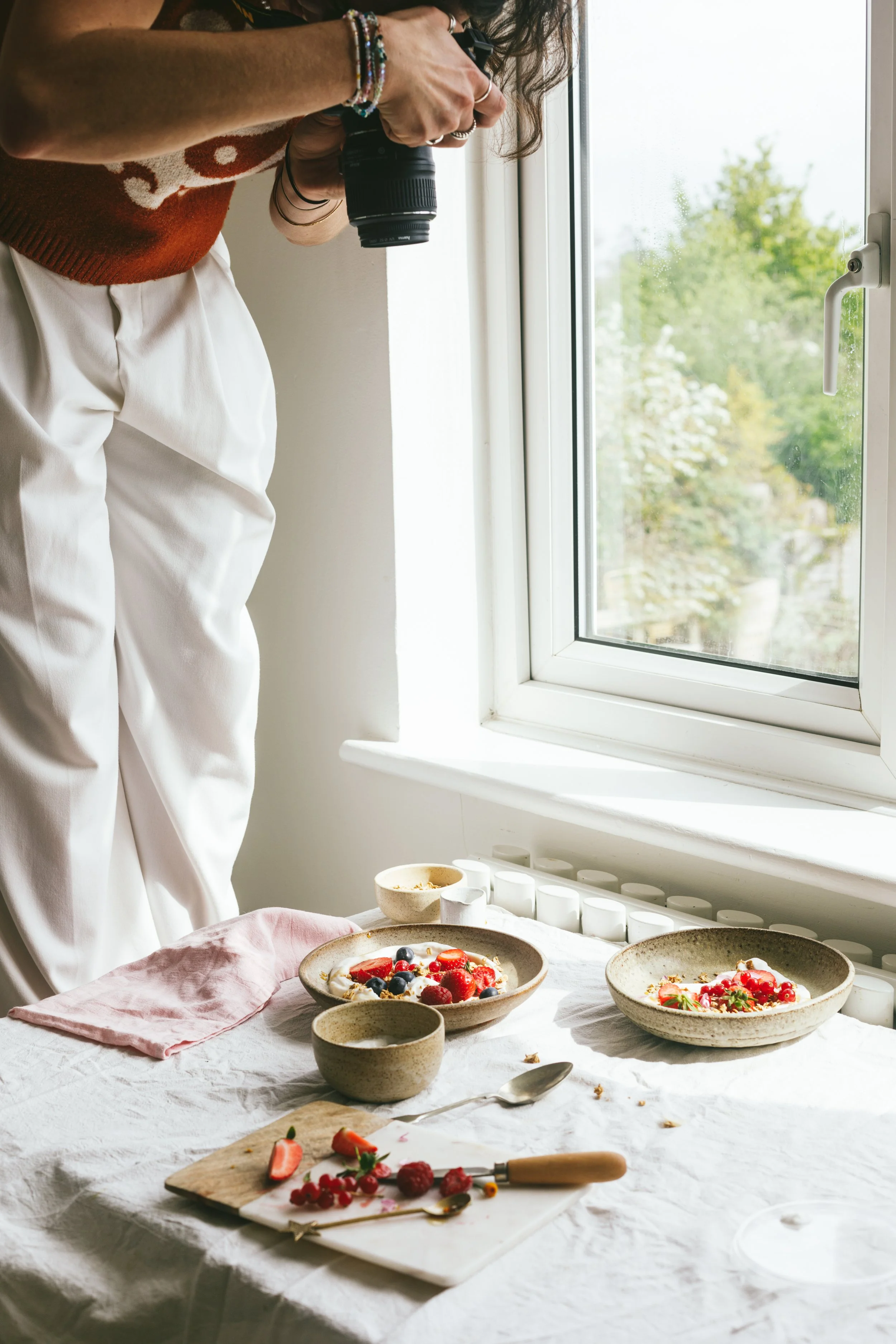 Image shows food content creation teacher Kimberly standing on a chair taking a photo of a food scene on a table