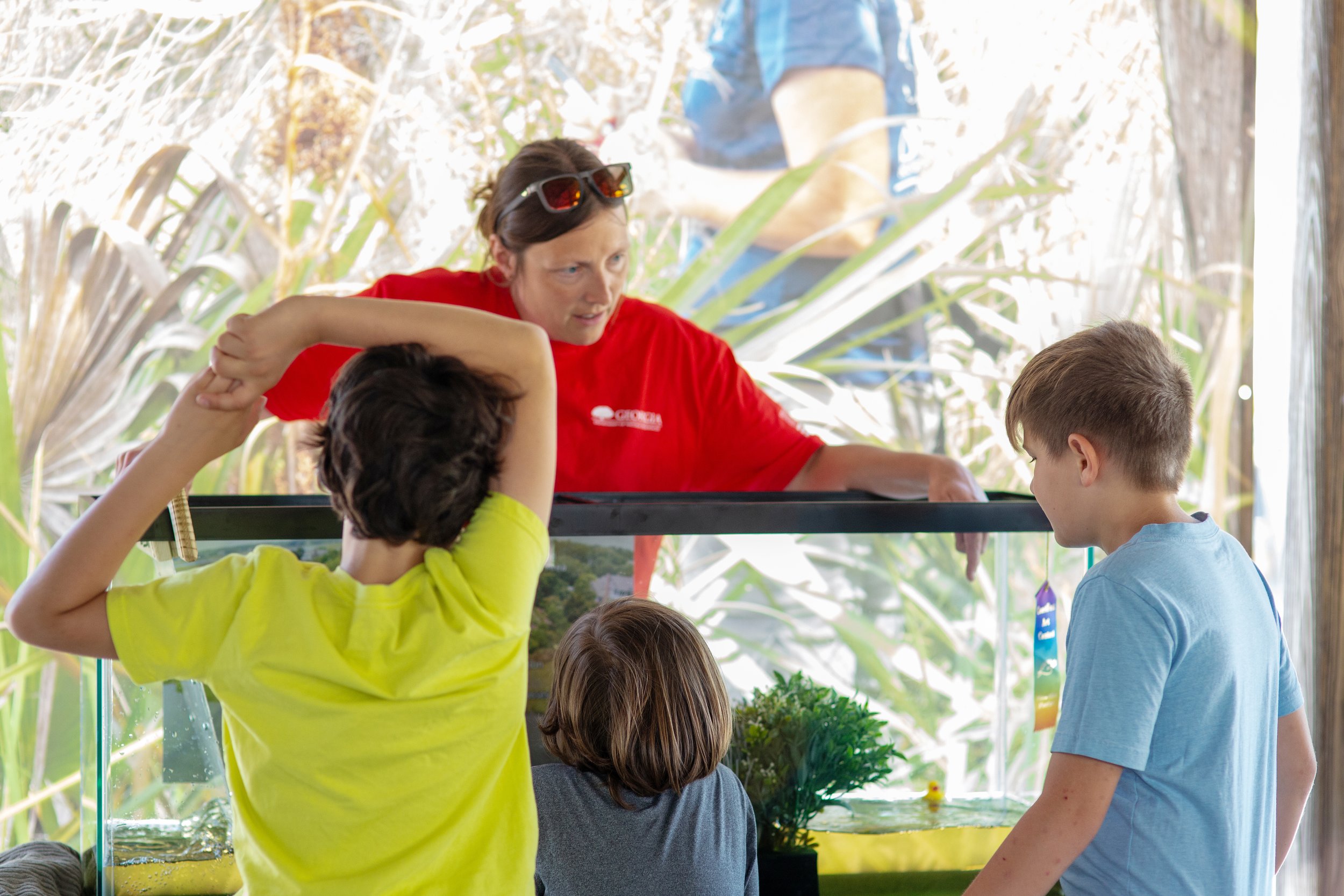 Children of various ages are engaged with a worker from the GA DNR during a tidal wave demonstration at the 2026 Coastfest event in Downtown Brunswick, GA