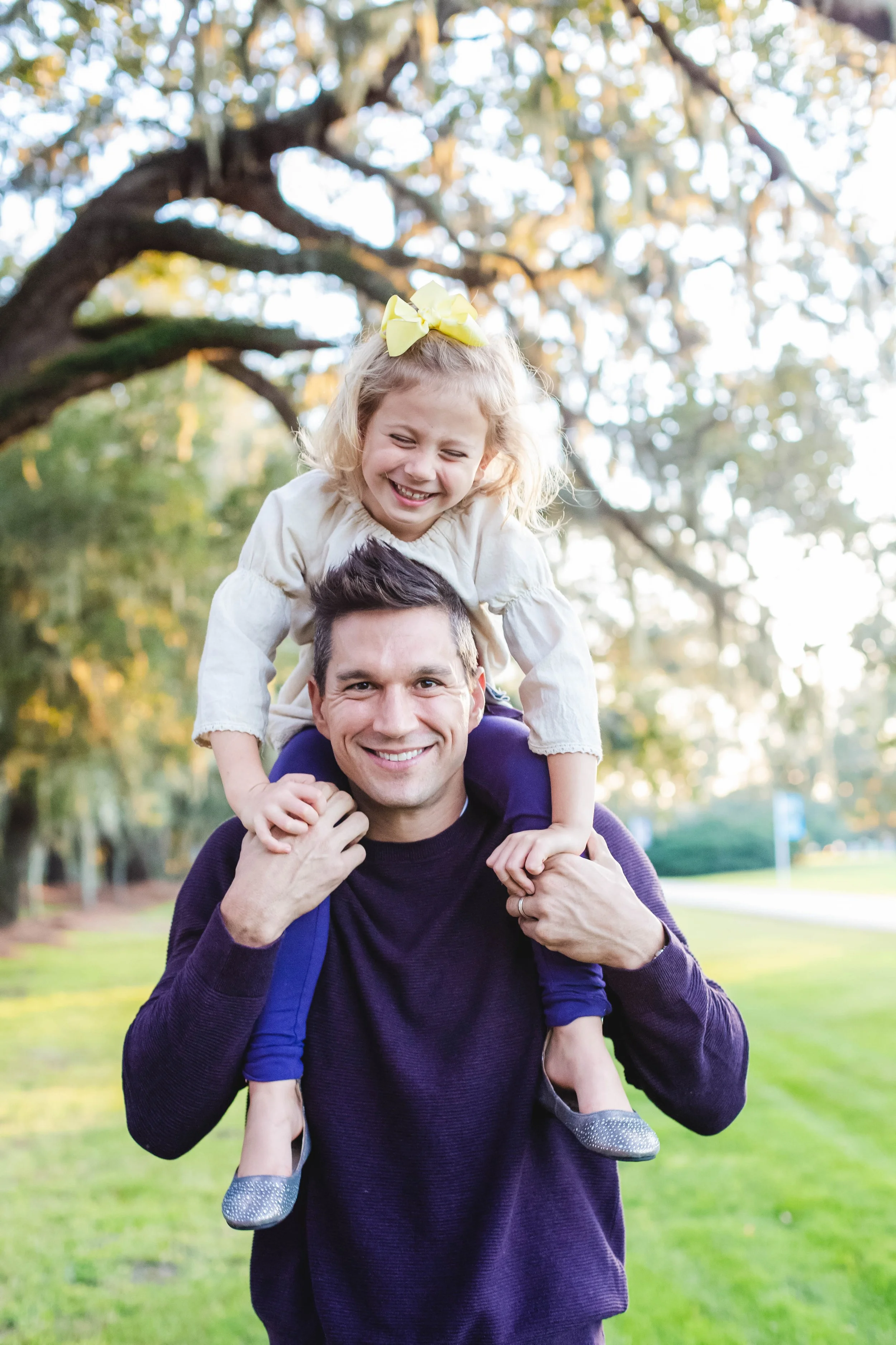 Father and daughter laughing together during a candid outdoor photography session at Avenue of the Oaks on St. Simons Island