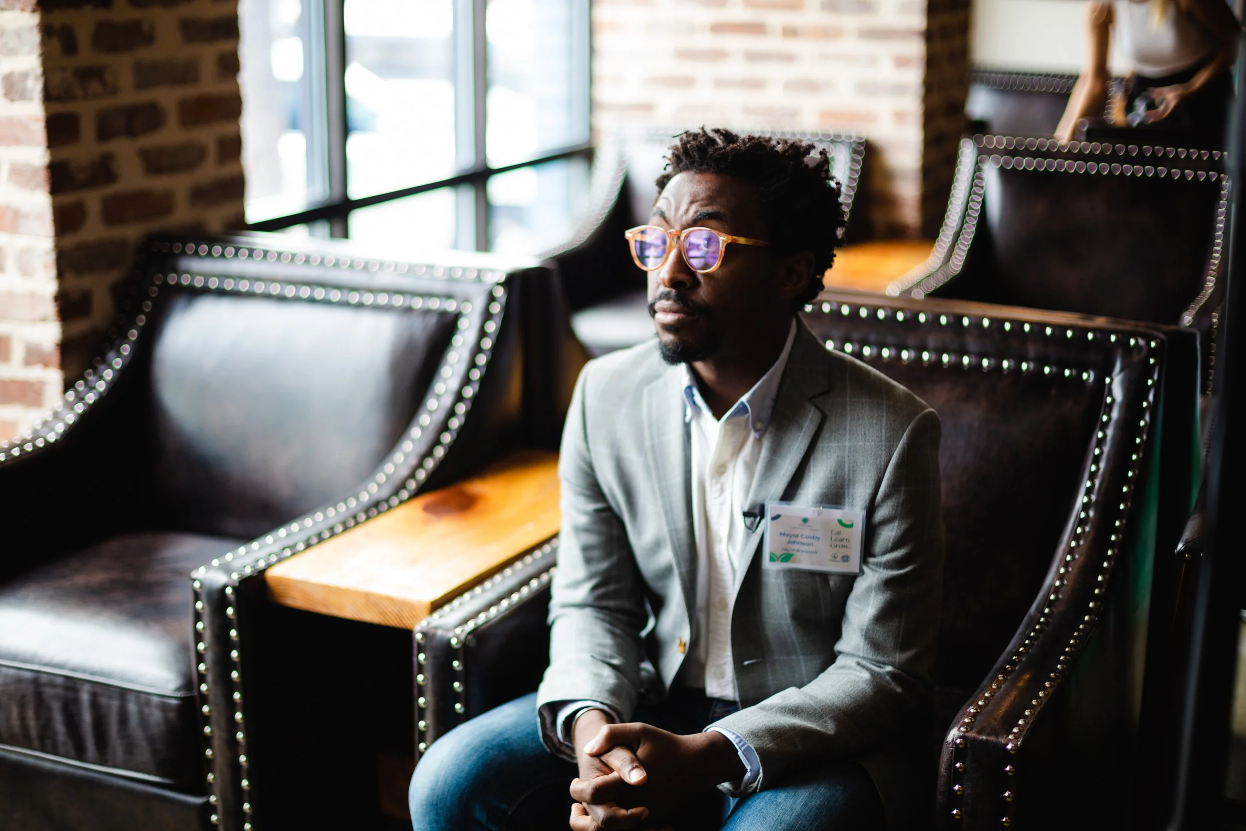 Man seated in a chair by a window, thoughtful personal branding portrait with natural light