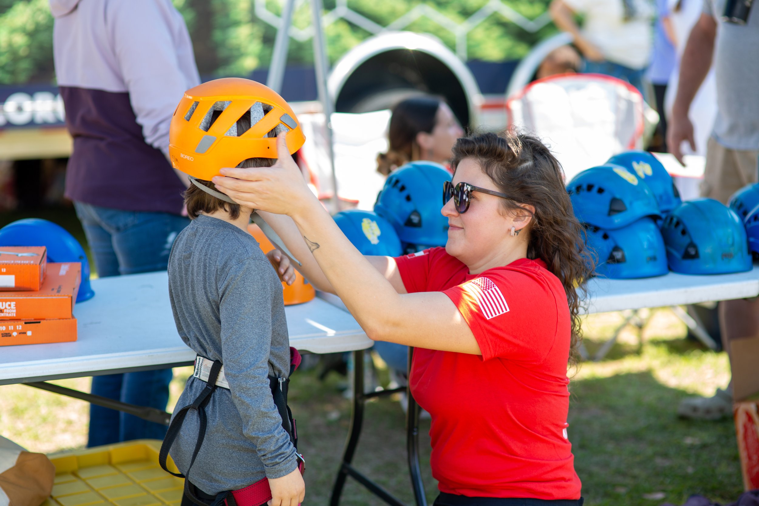 A young child is being fitted with safety equipment at the 2026 Coastfest Event in Downtown Brunswick before he goes rockclimbing