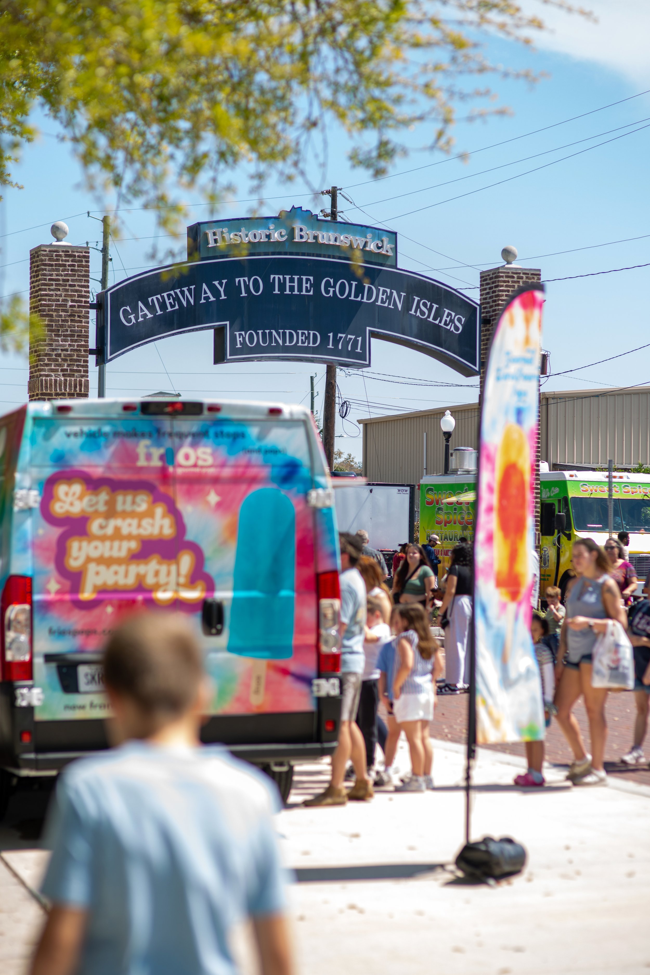 Food trucks sit at the entrace of the Mary Ross Waterfront Park. The sign reads, "Historic Brunswick. Gateway to the Golden Isles. Founded in 1771."