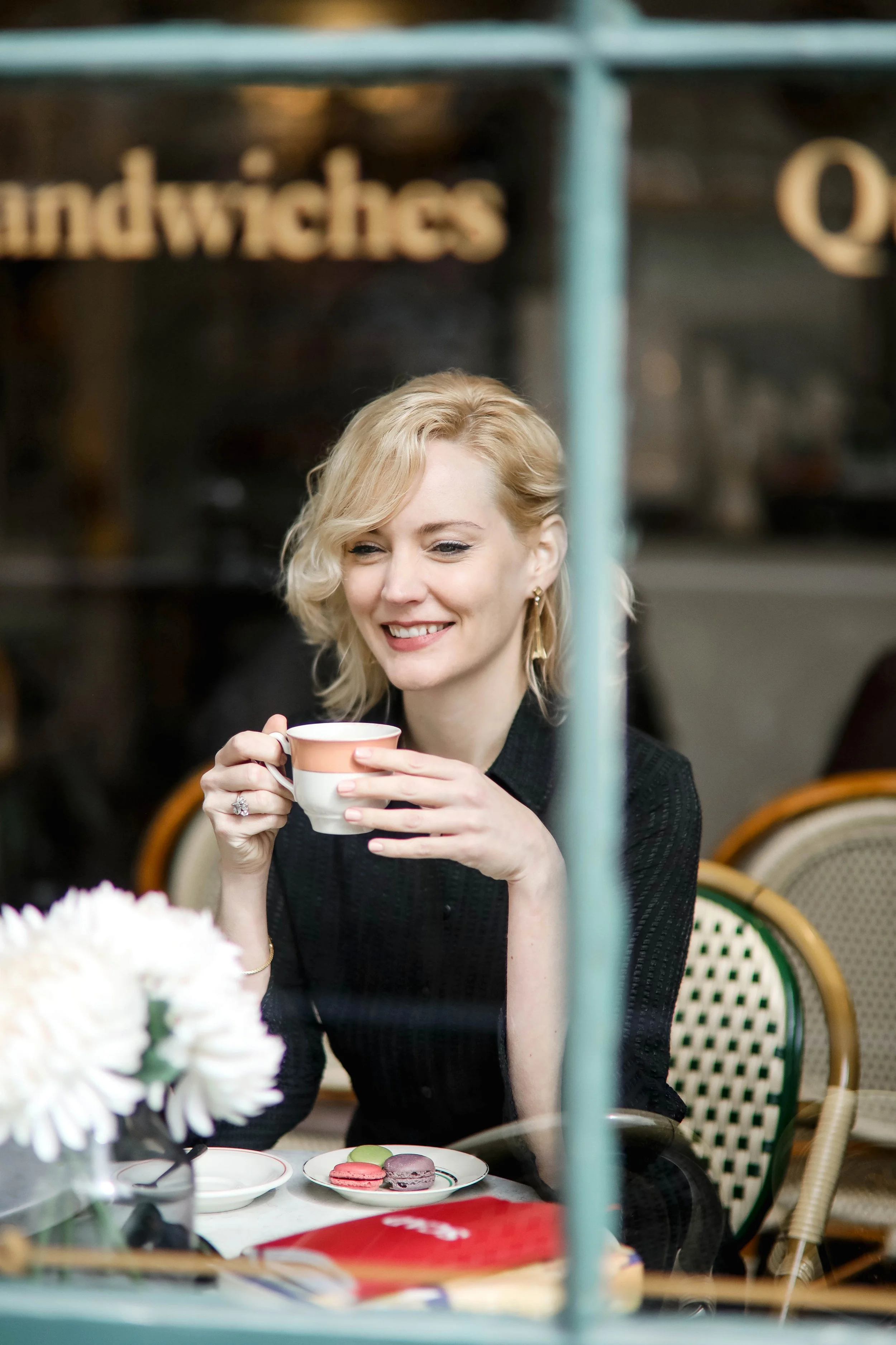 Woman enjoying coffee at a cafe window, candid lifestyle brand photography moment