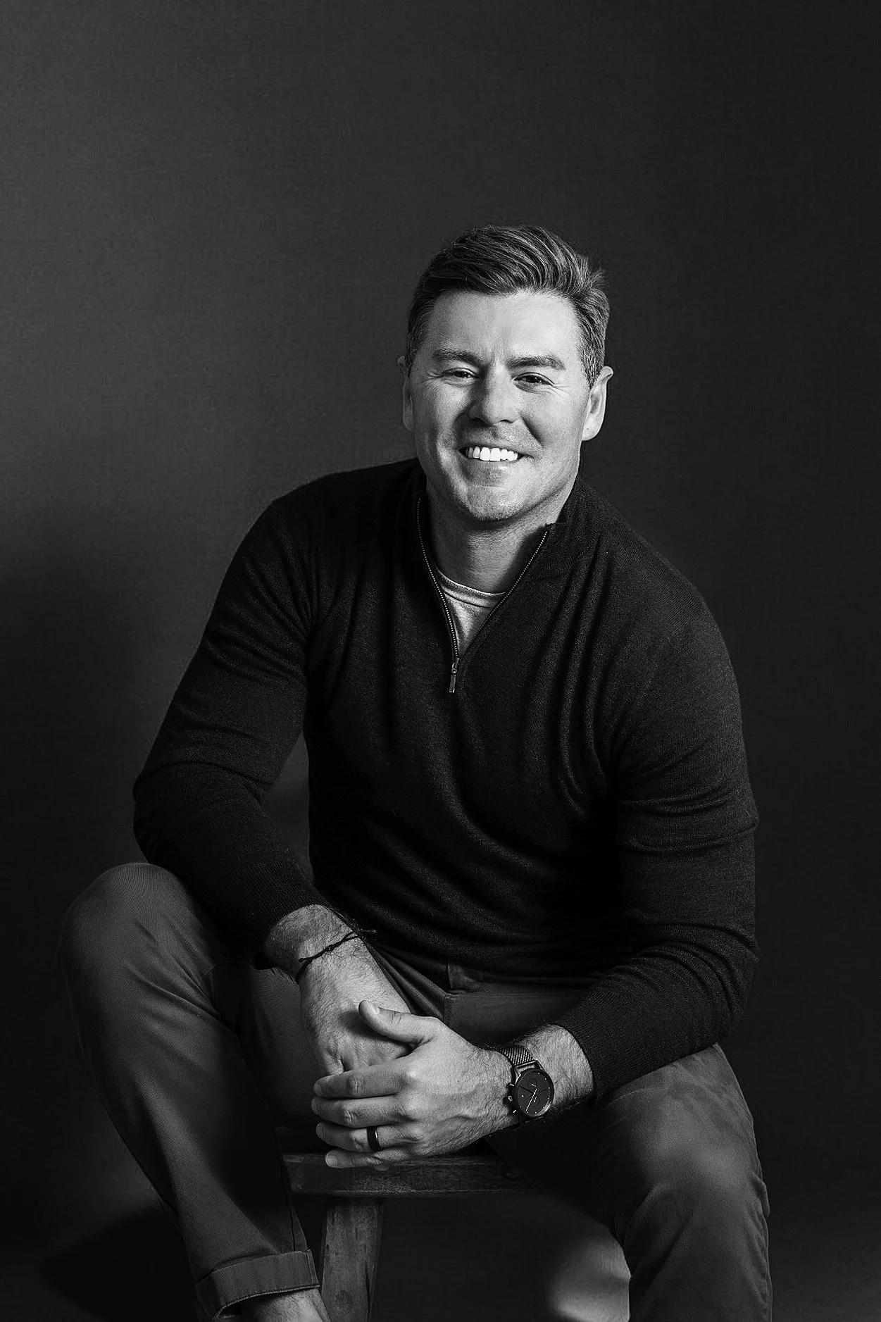 Professional man seated and smiling, black and white brand portrait