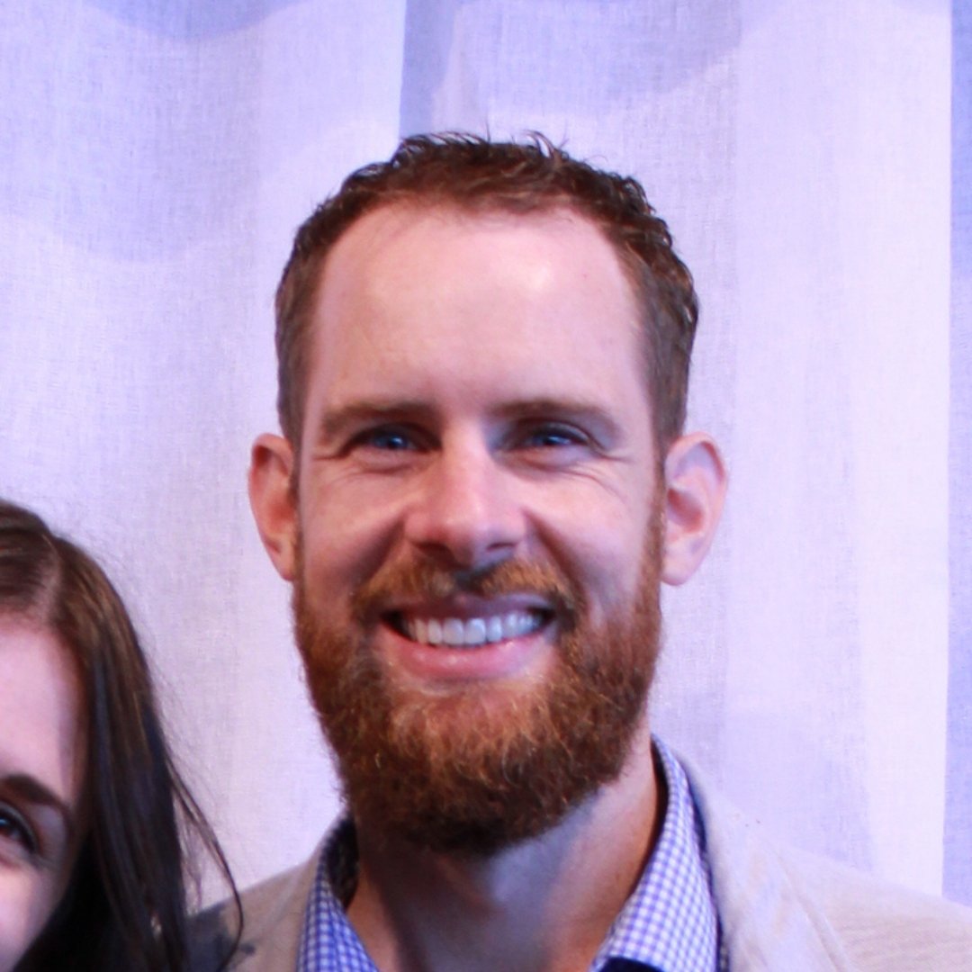 Smiling bearded man in a blazer and checkered shirt