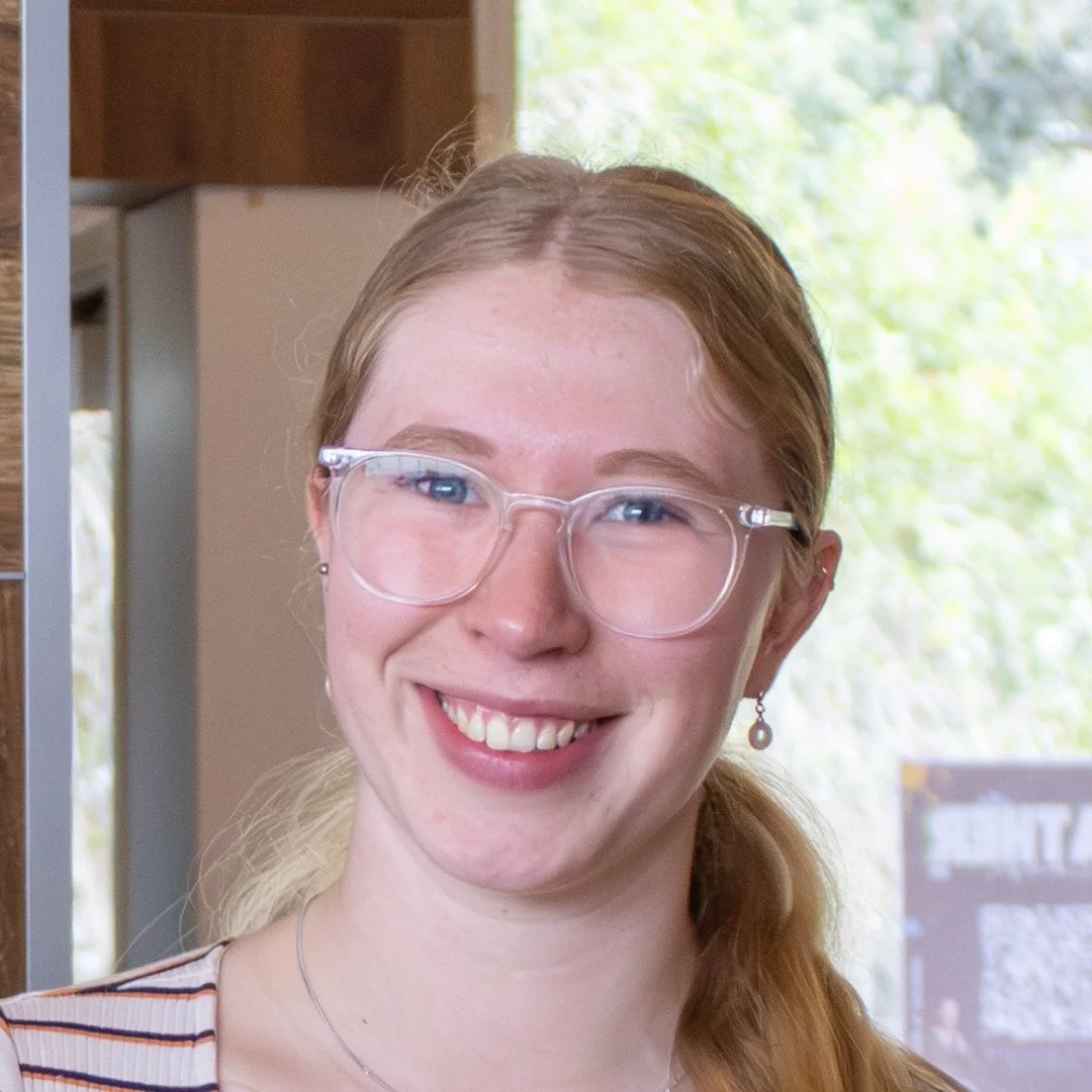 Smiling woman wearing clear eyeglasses and earrings indoors