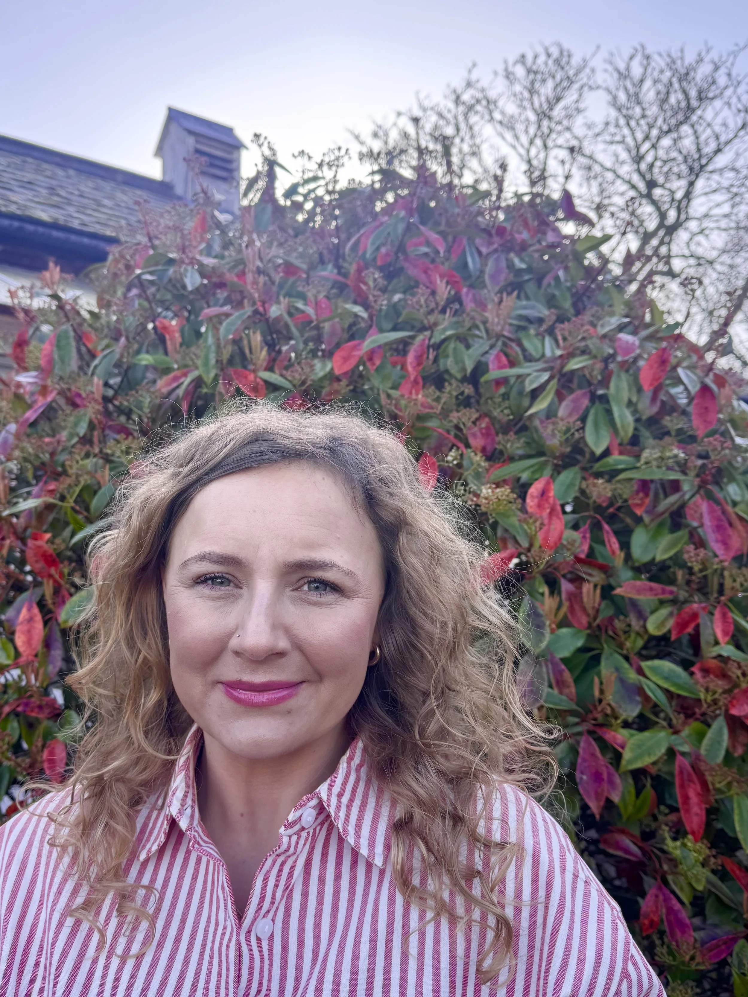 Sylvie, Kitchen Supervisor and baking specialist smiling in the Two Teaspoons garden in Wimbledon.