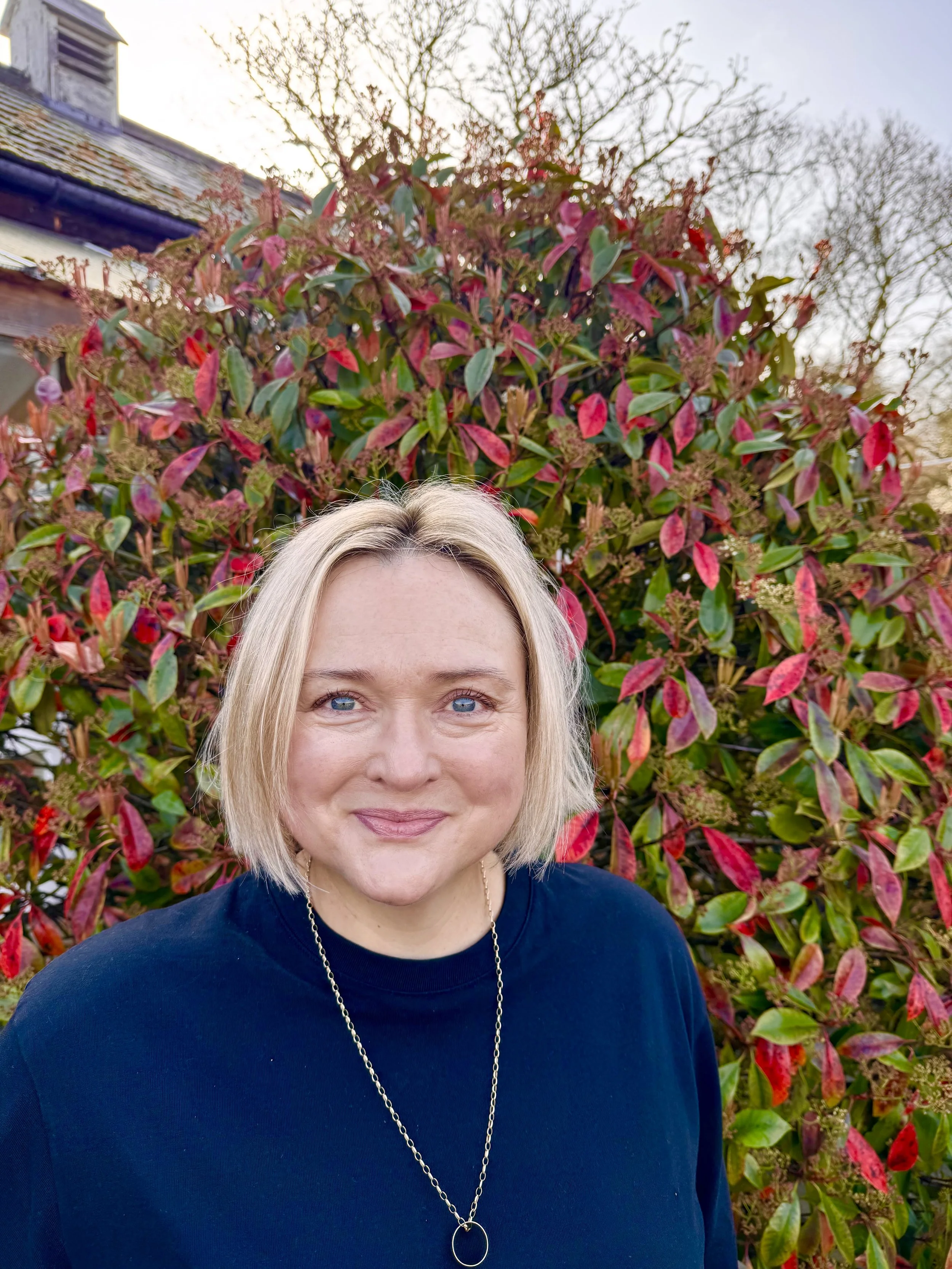 Becky, Founder of Two Teaspoons smiling in the garden of the kitchen in Wimbledon.