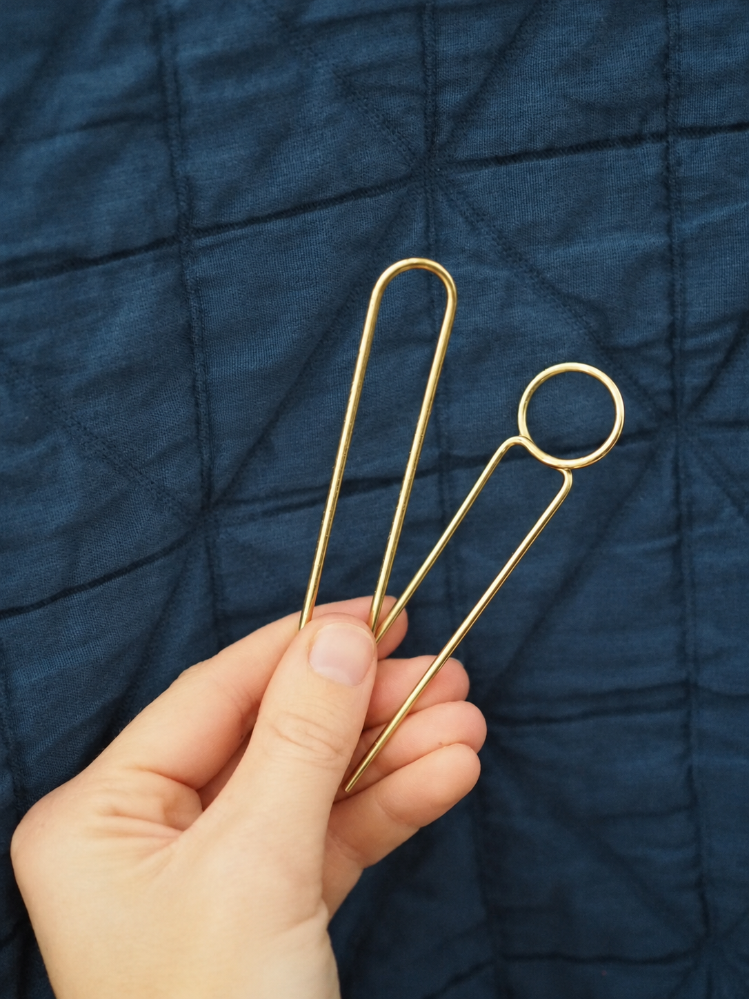 Hand Holding Brass Loop Pins.png