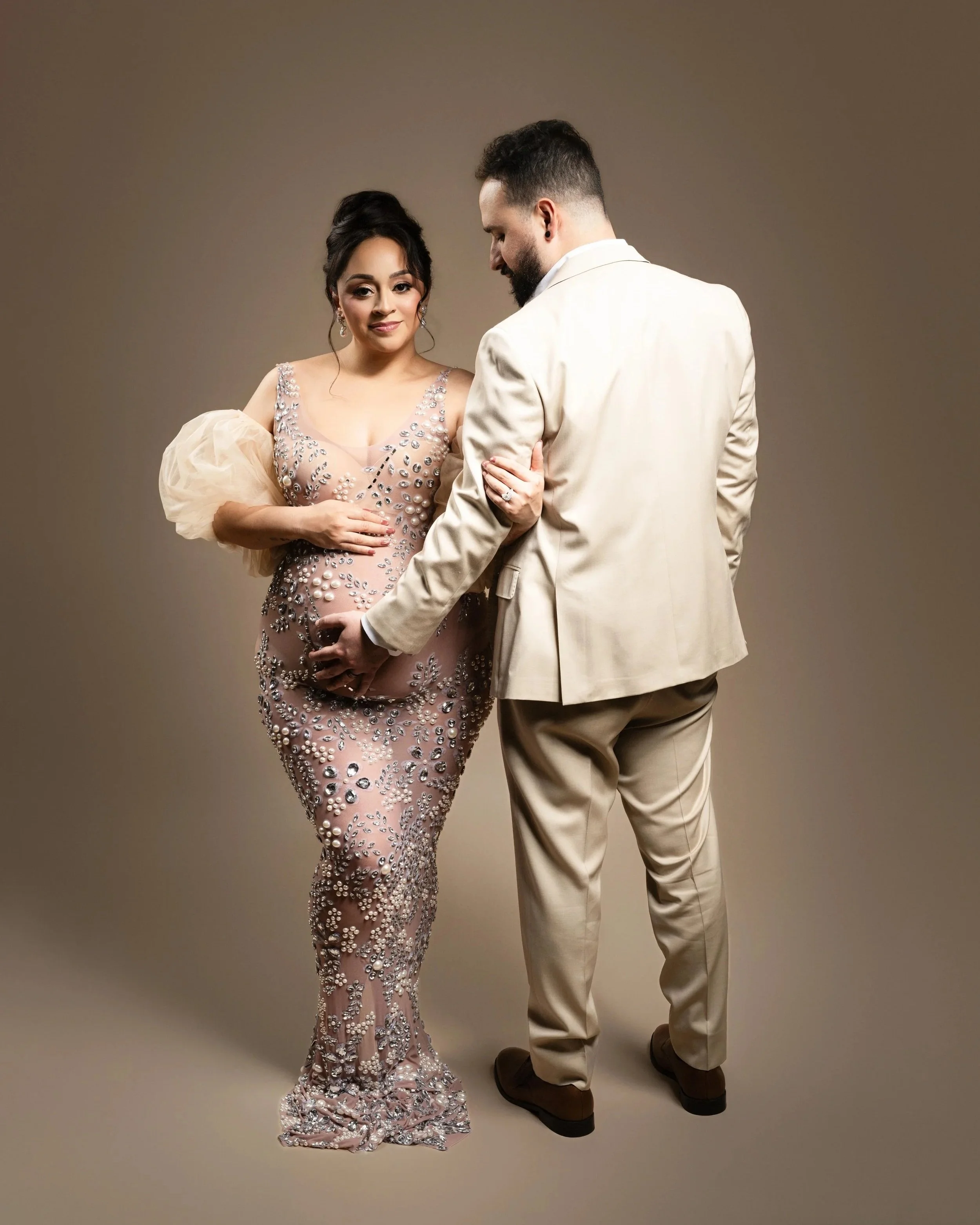 Expectant couple posing together for an elegant maternity portrait in a Dallas photography studio.