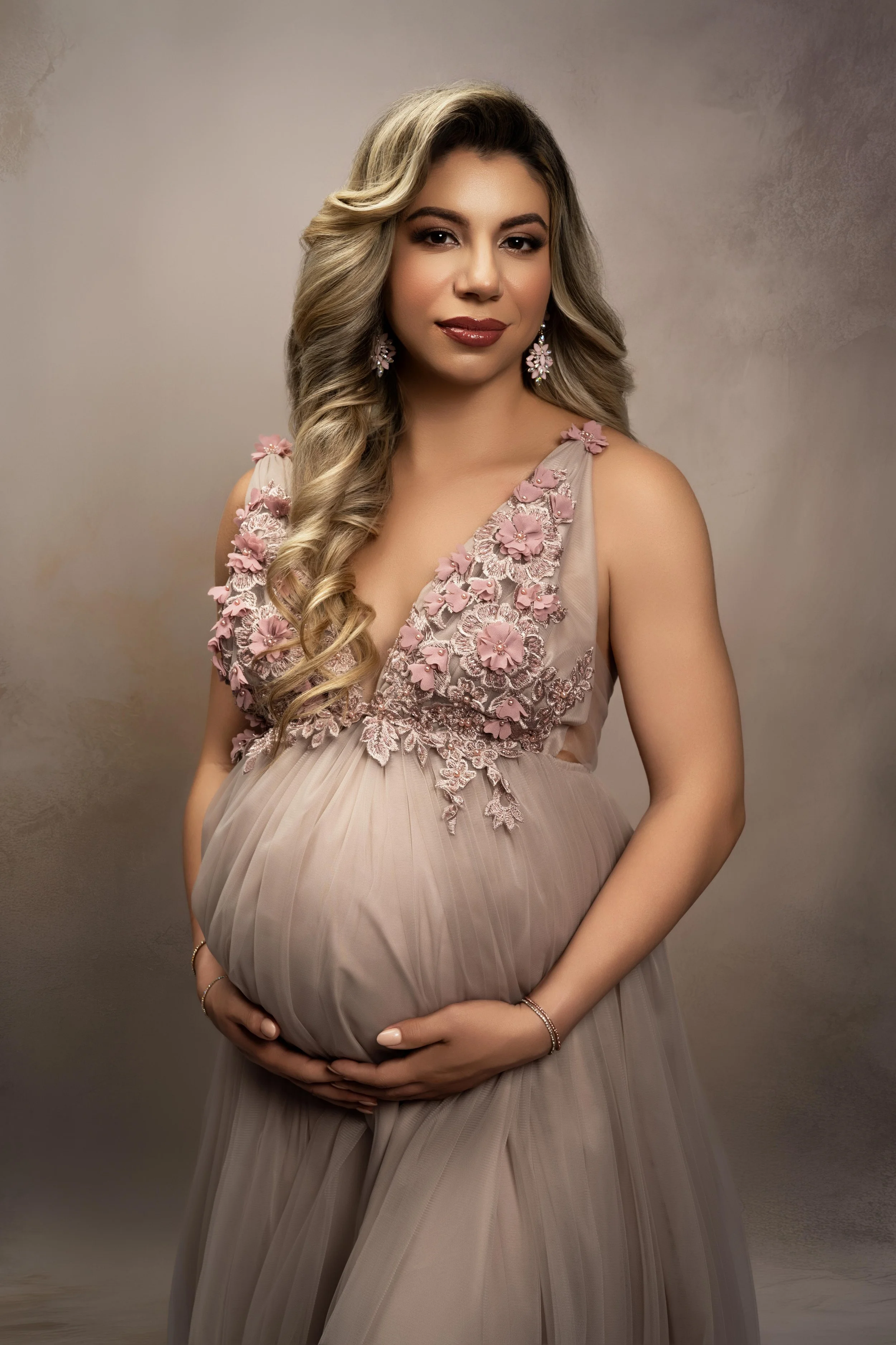 Soft, feminine maternity portrait in a floral gown, photographed in a North Dallas studio.