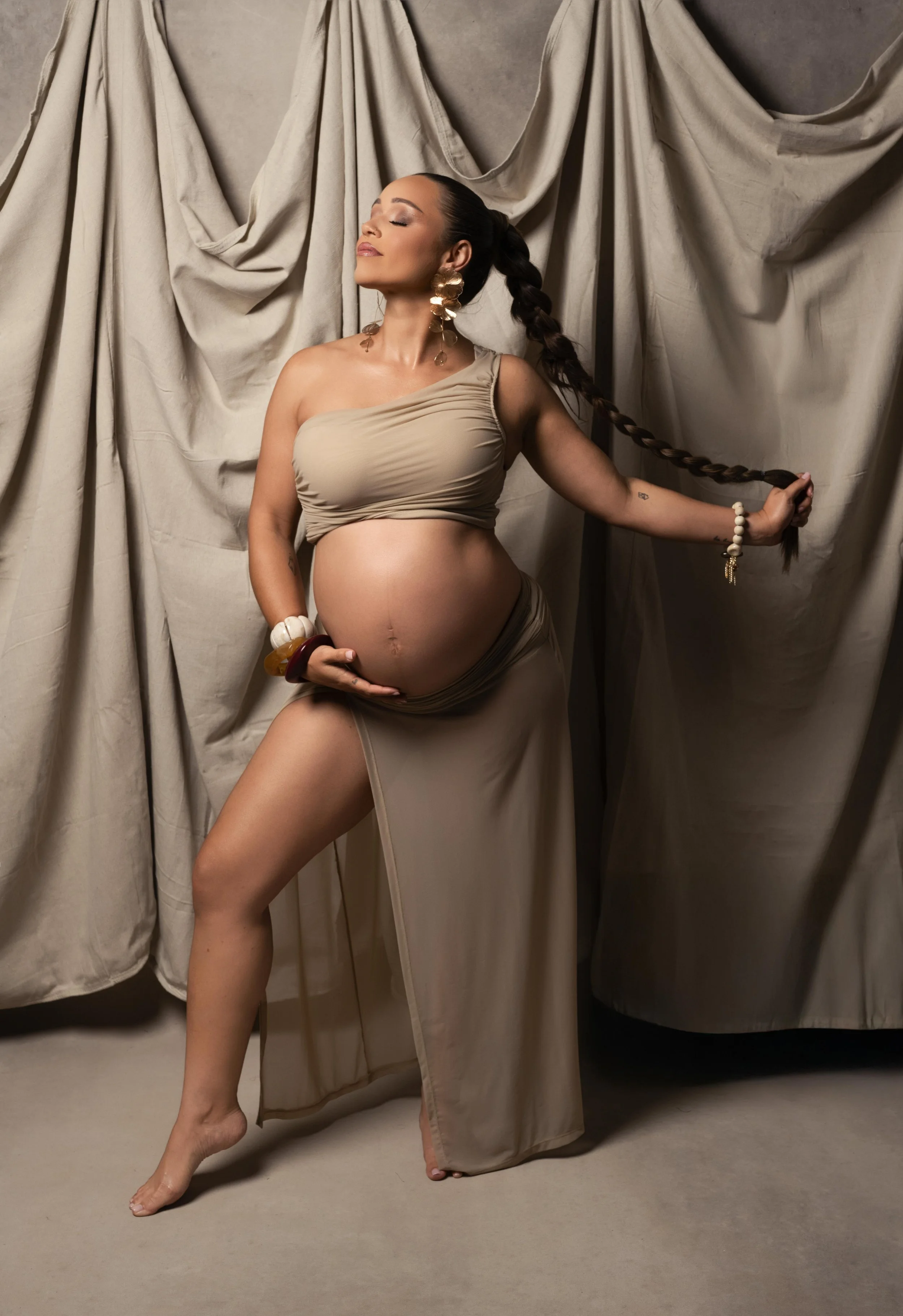 Elegant studio maternity portrait with neutral draping and fashion-inspired styling, photographed in Plano, Texas.