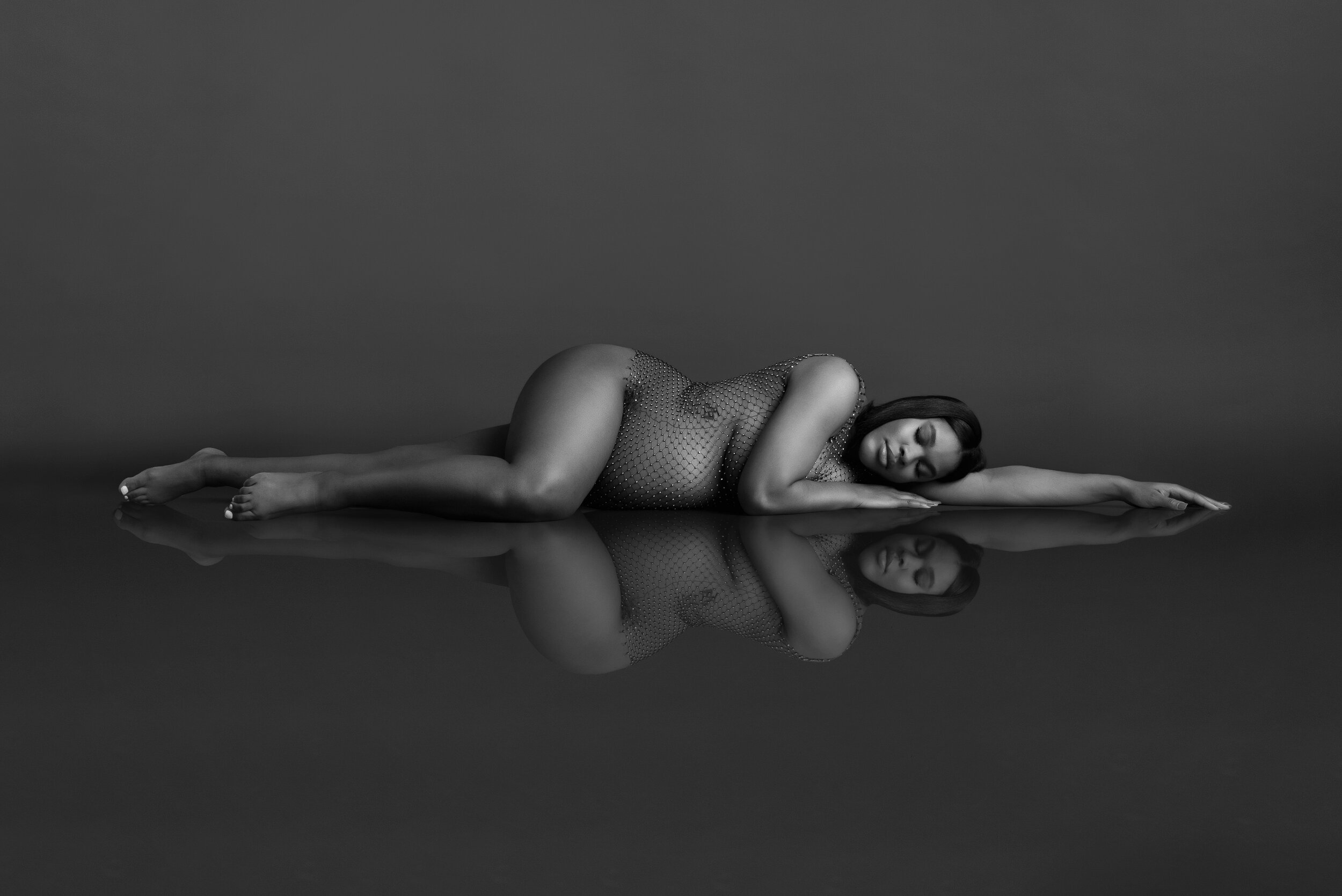 stunning black and white fine art maternity laying down pose with reflection shot at Ana Lanier Portrait Studio in Dallas TX