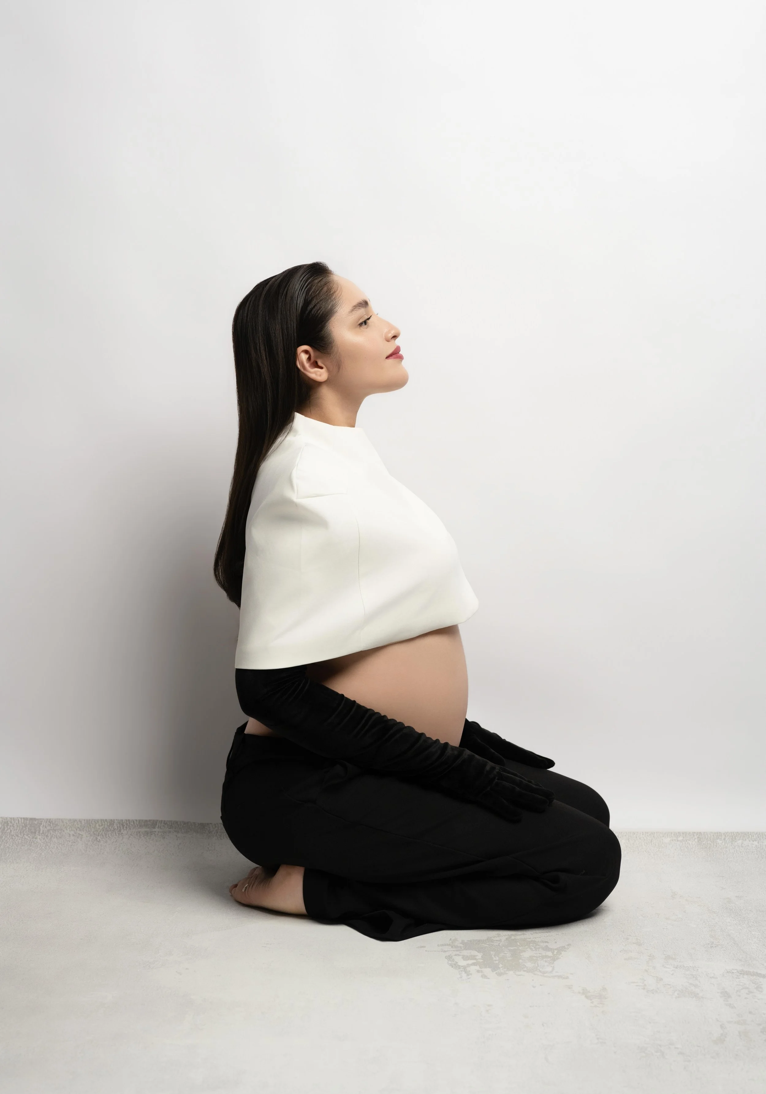 Dallas maternity portrait featuring a mother-to-be in a modern black-and-white look with soft, minimalist studio styling.