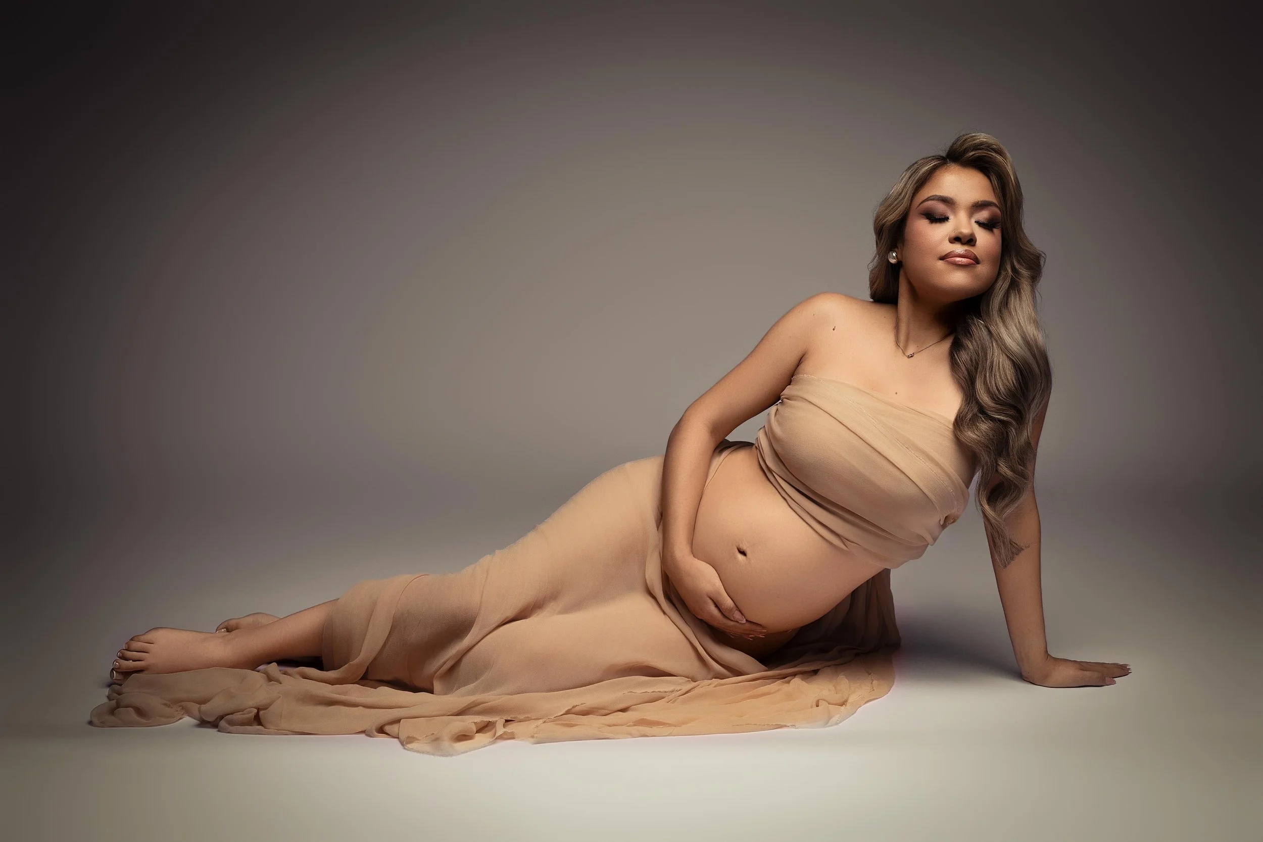 Soft, elegant maternity portrait in neutral draping, photographed in a Dallas, Texas maternity photography studio.