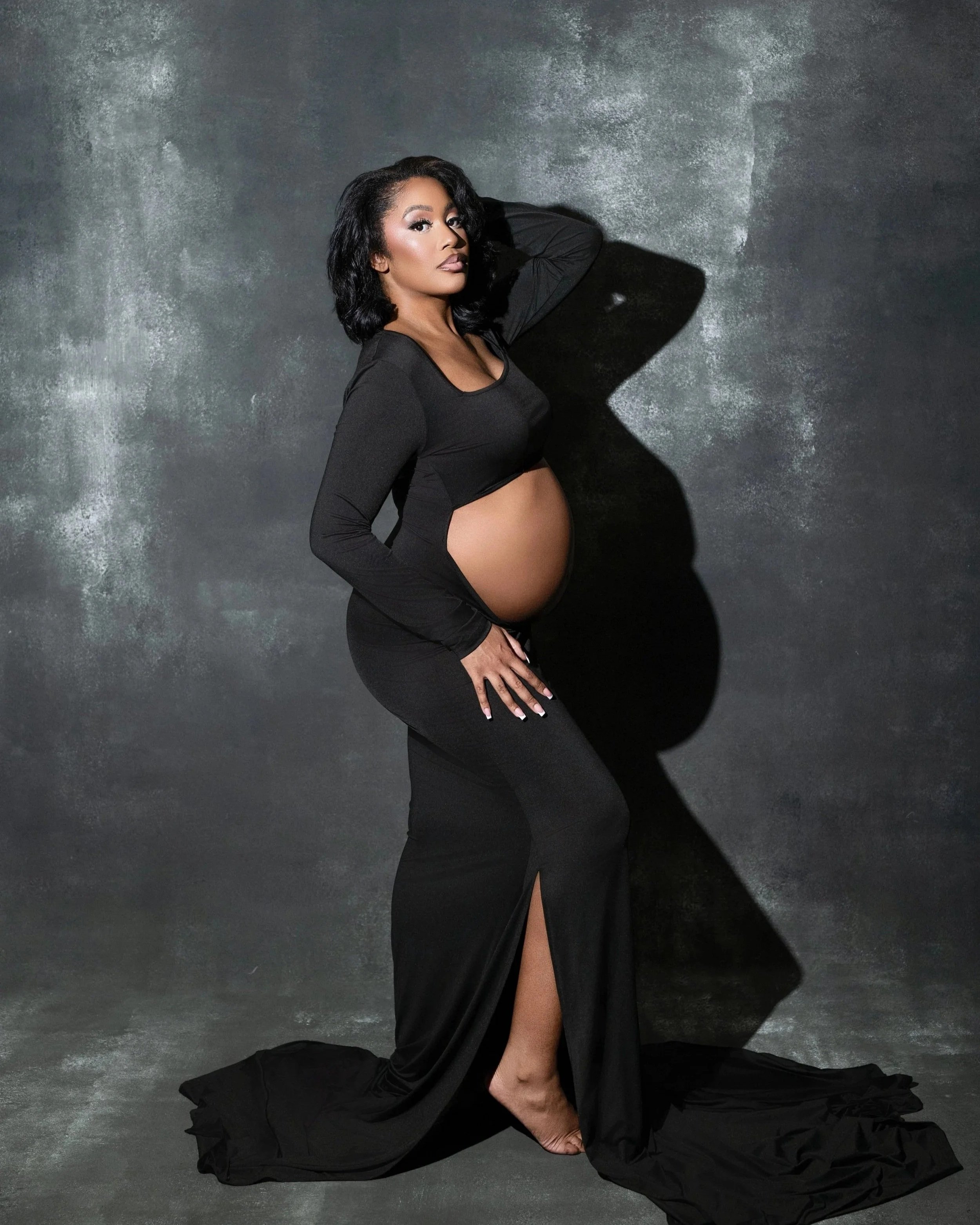 Pregnant woman in a black gown posing in studio during a Dallas maternity photography session.