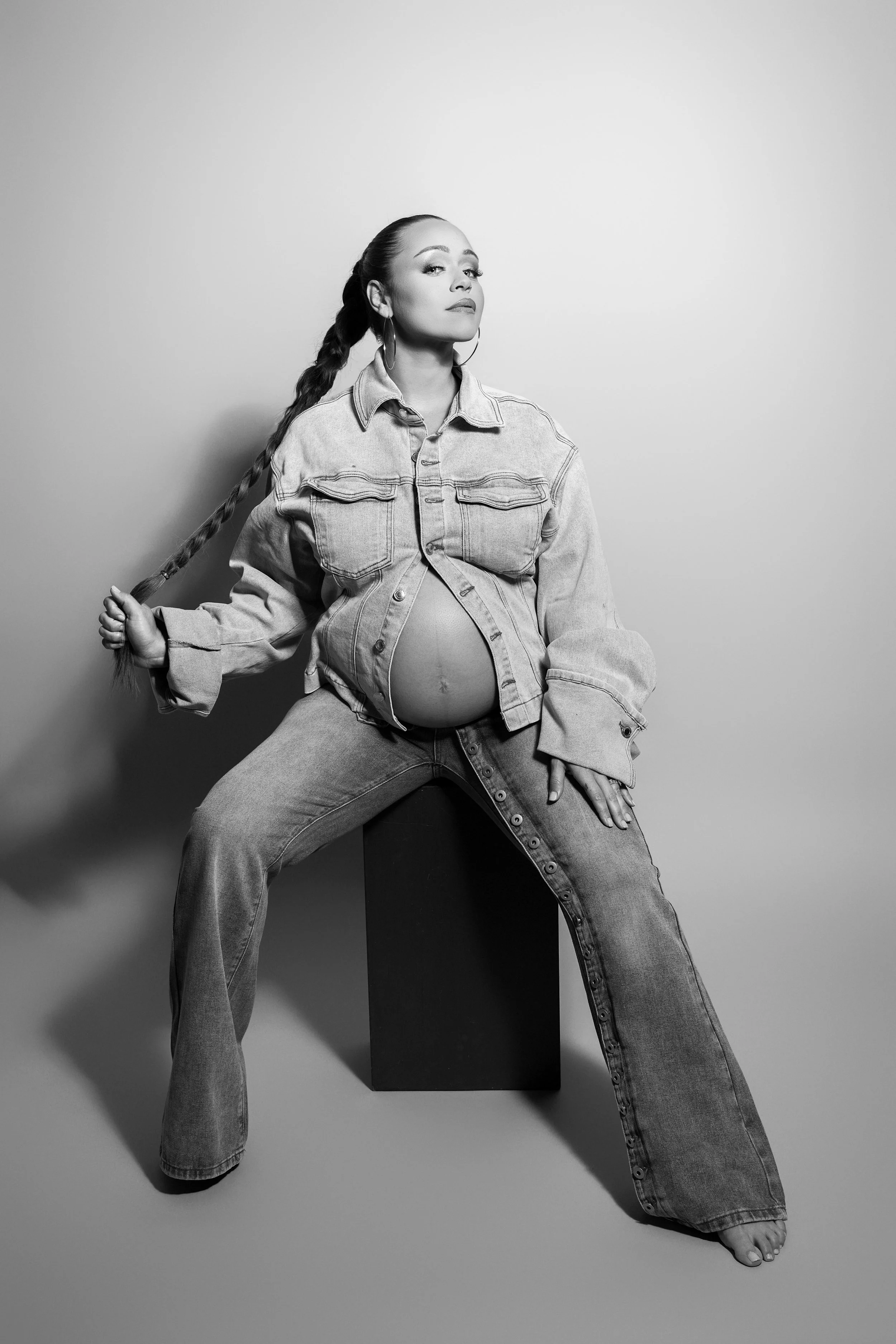 Black and white editorial maternity portrait featuring a pregnant mother in a modern fashion-forward look.