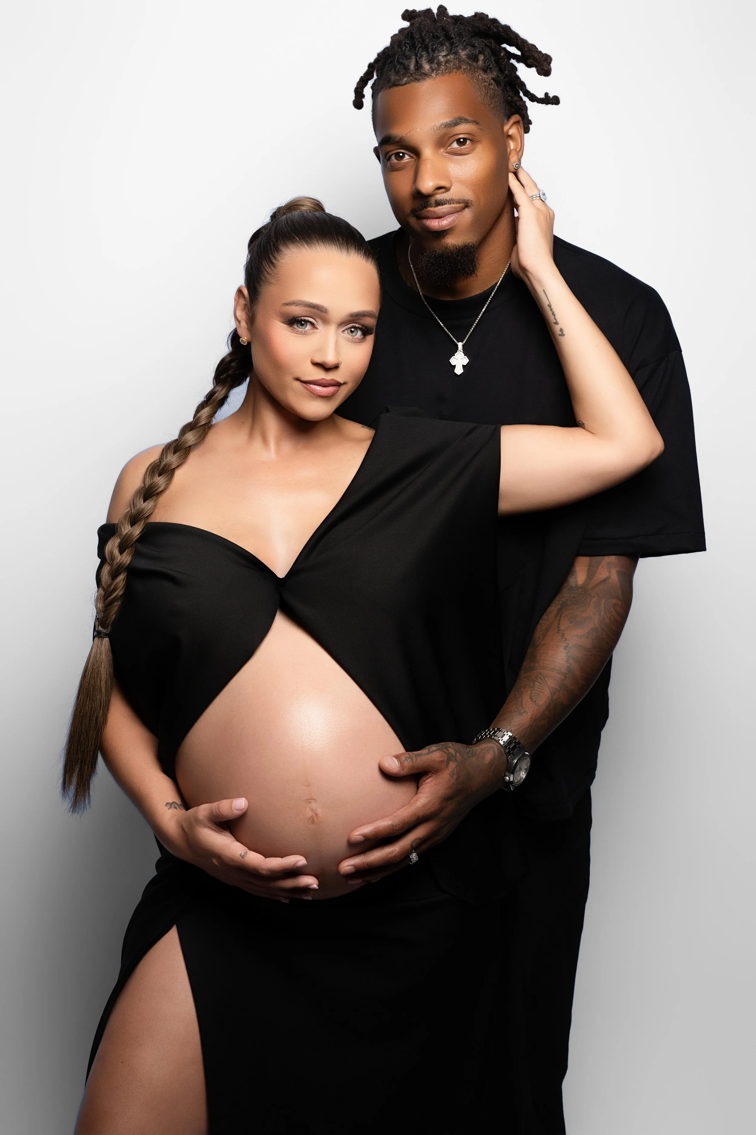 Studio maternity portrait of an expectant couple in coordinated black outfits, photographed in Dallas.